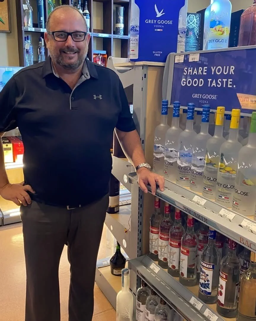 Scenic landscape with a lake, green hills, and mountains under cloudy sky.