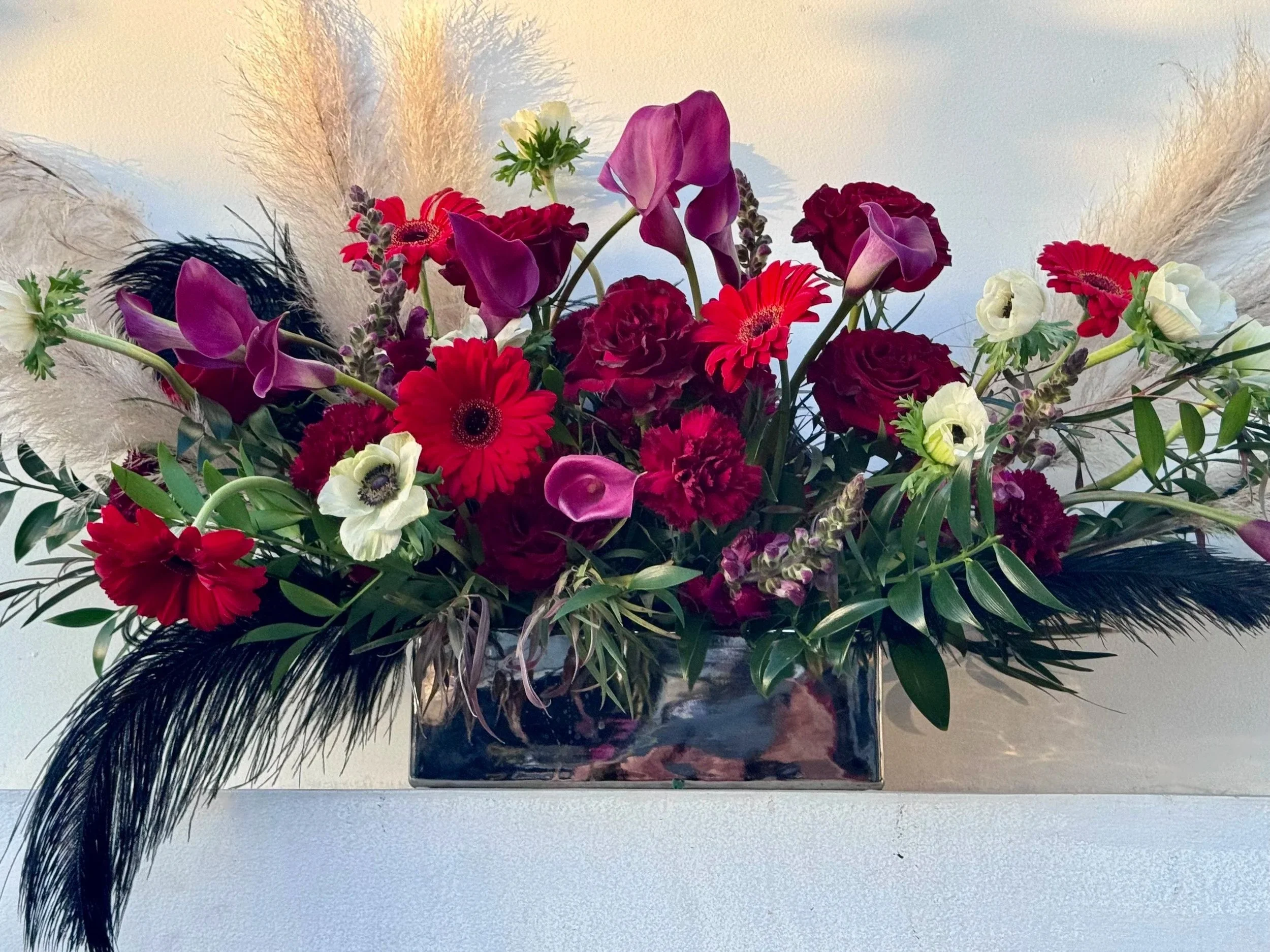 moody jewel tones, red roses, burgandy cala lilies, feathers, pampas grass