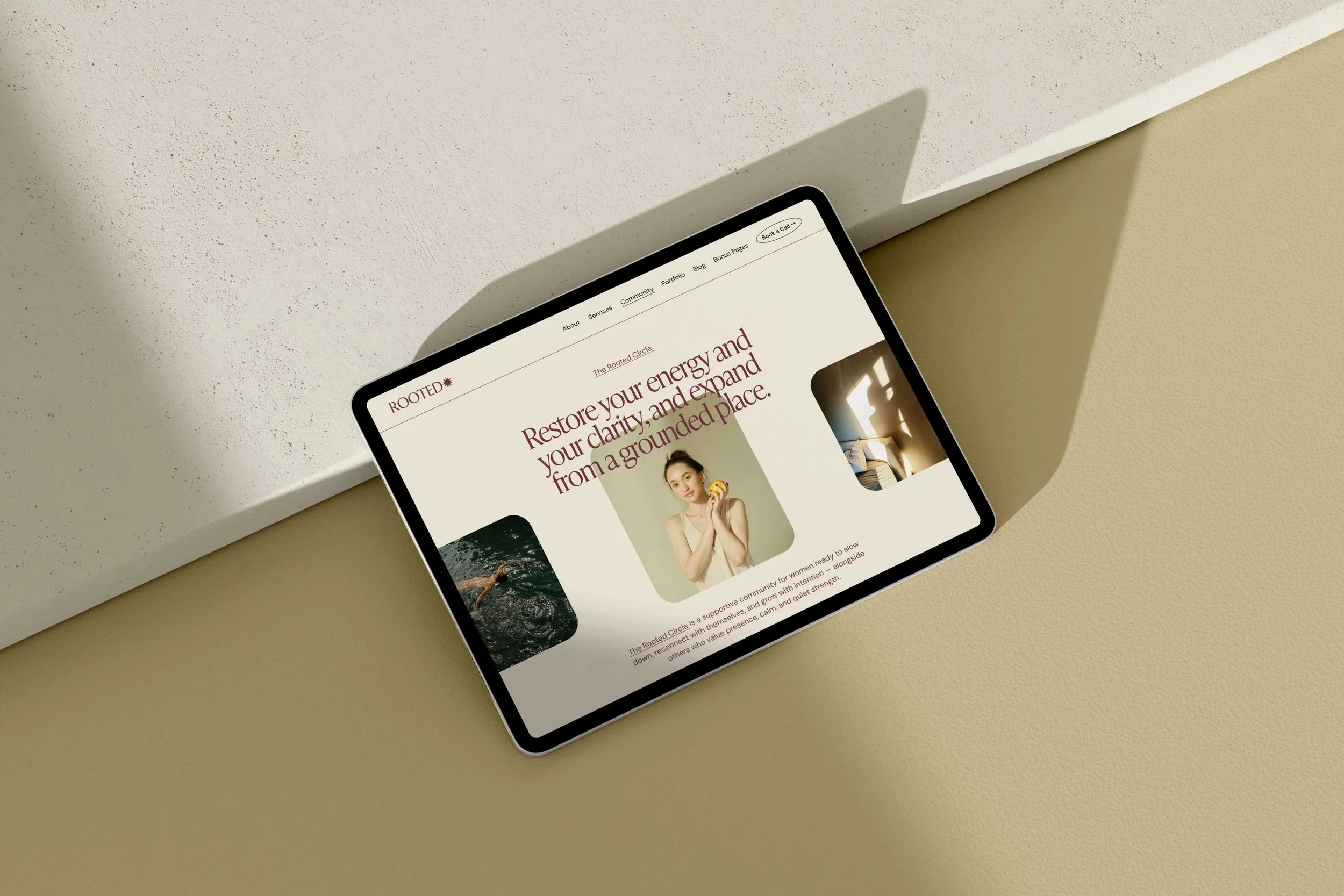 Tablet on a beige surface displaying a website with the heading 'Restore your energy and your clarity, and expand from a grounded place' and an image of a woman holding a yellow object.