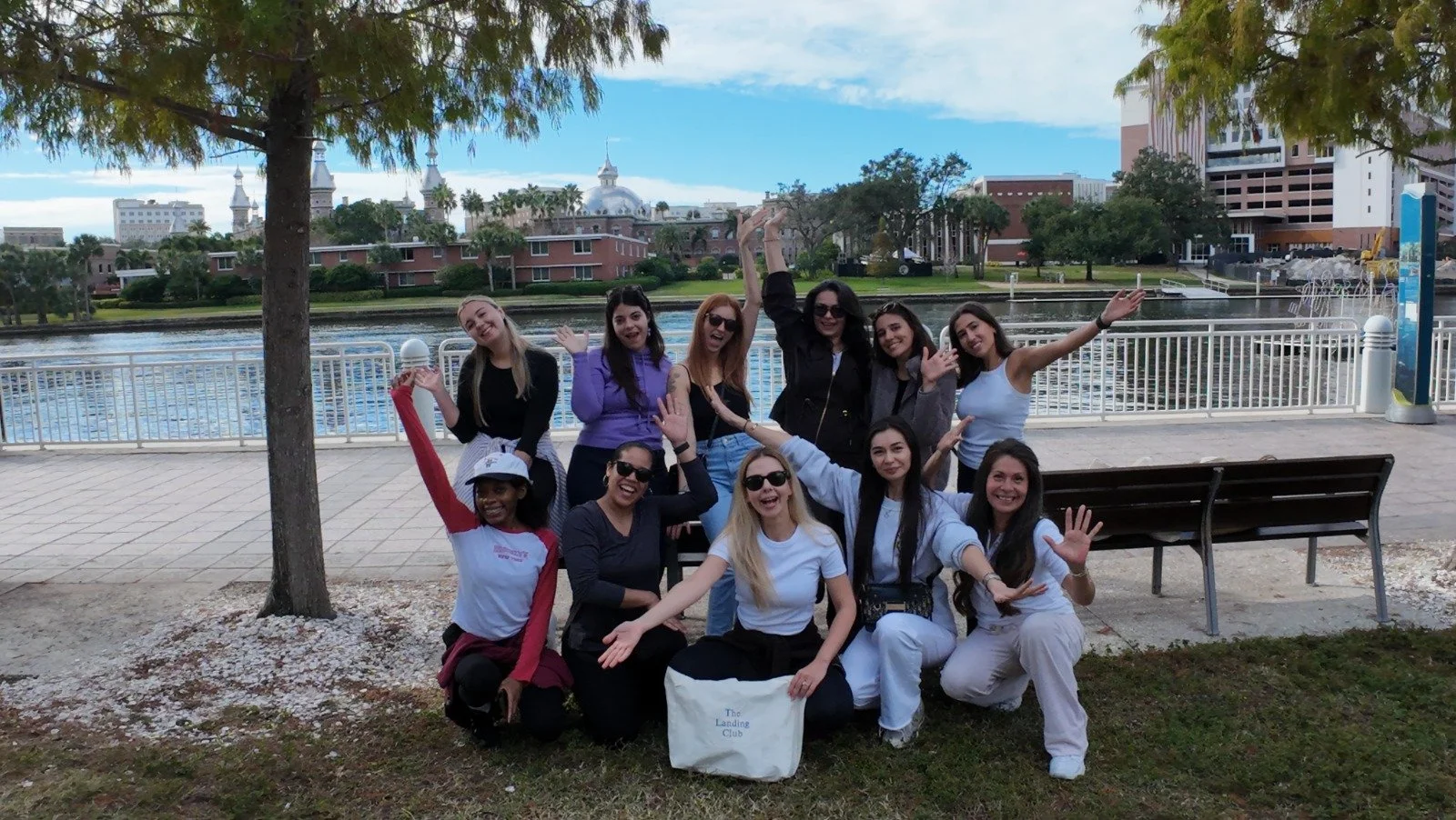 Scenic view of a lake surrounded by rolling hills and towering mountains under a cloudy sky.