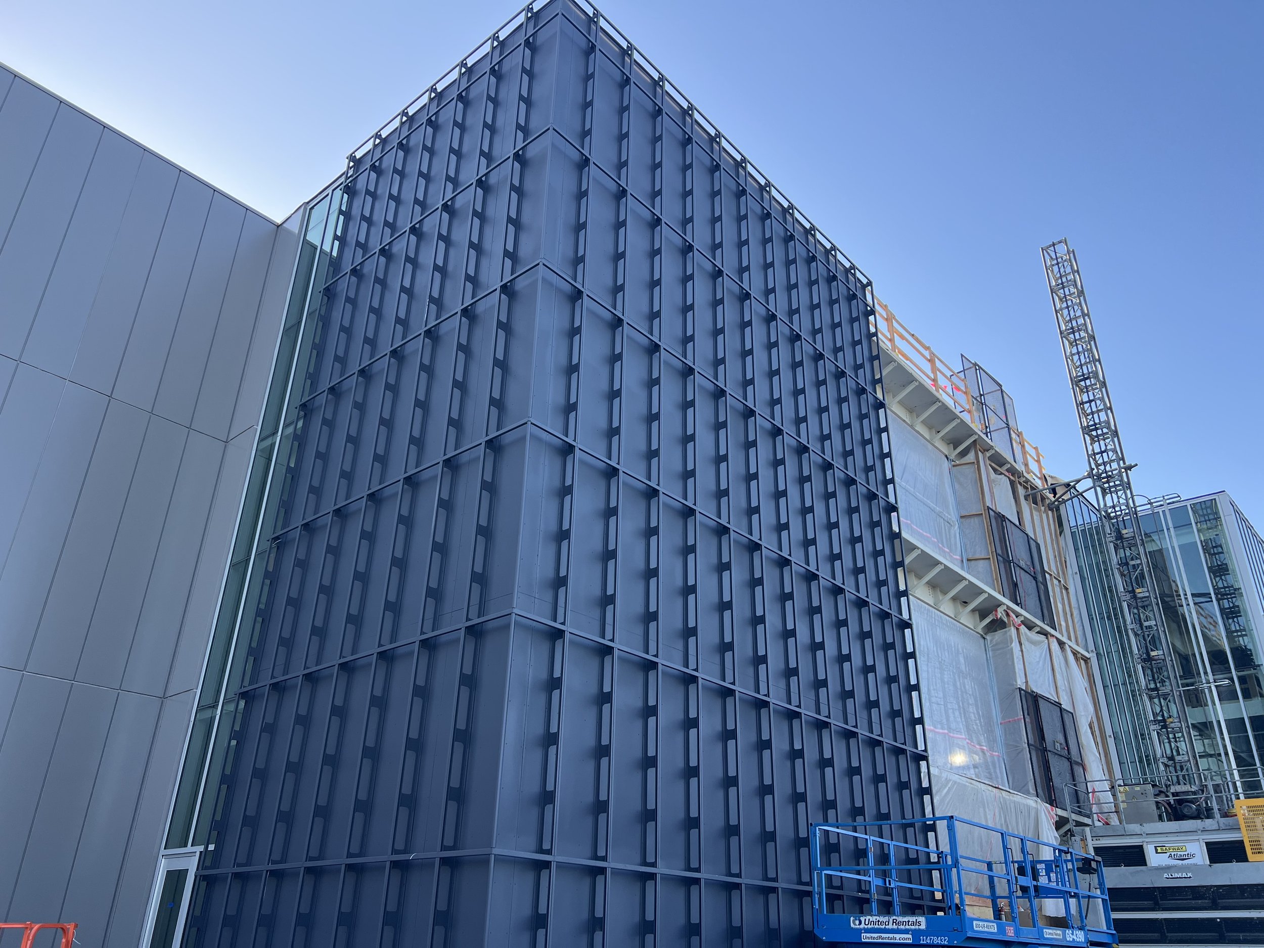 Modern building under construction with glass panels and a construction crane.