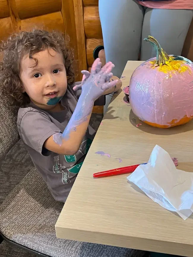 Young girl painting a pumpkin pink.