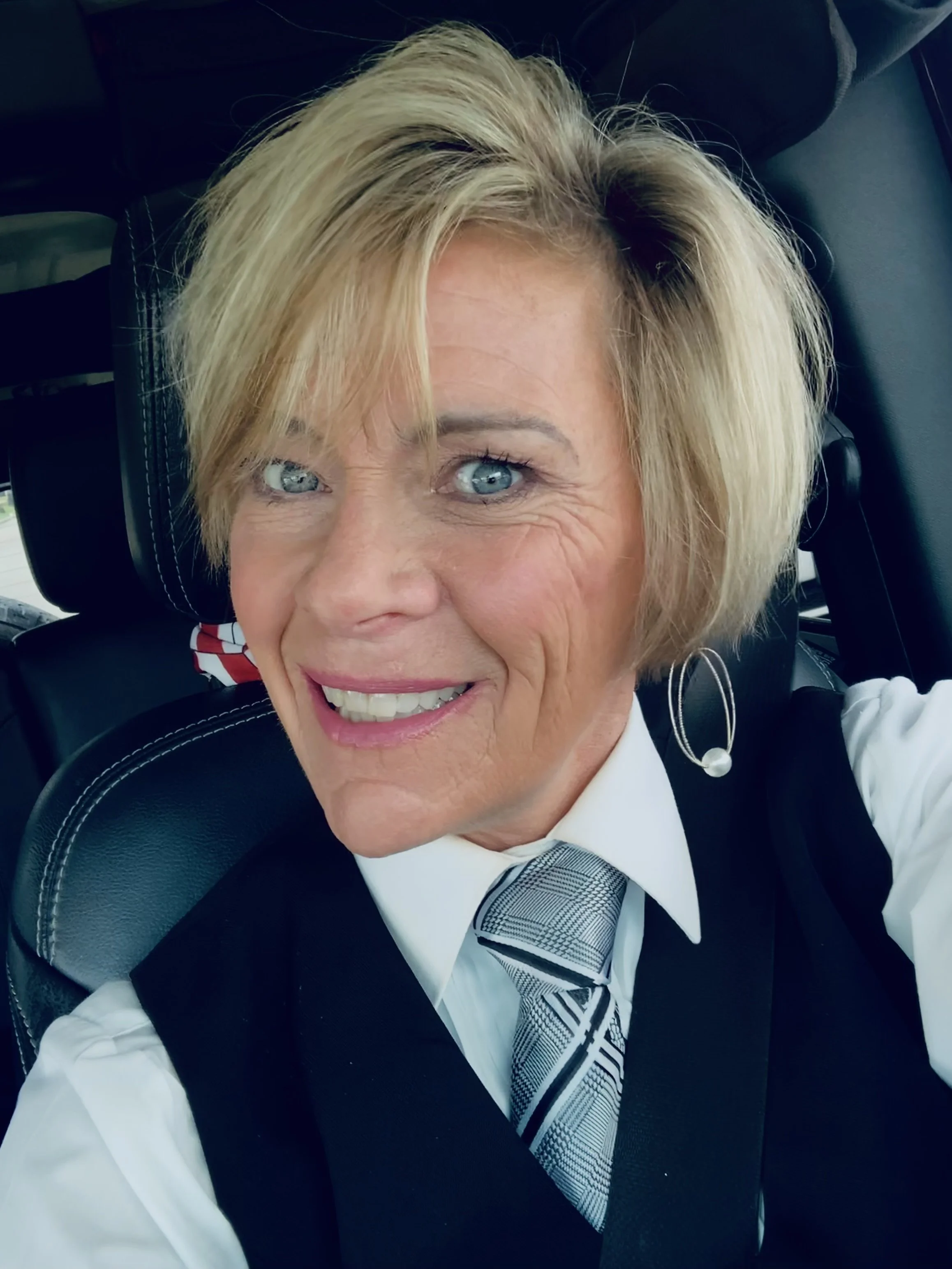 Keepsake & Co. Events Officiant, Teresa Medina, blonde hair and blue eyes, wearing a white shirt, a black vest, and a striped tie.