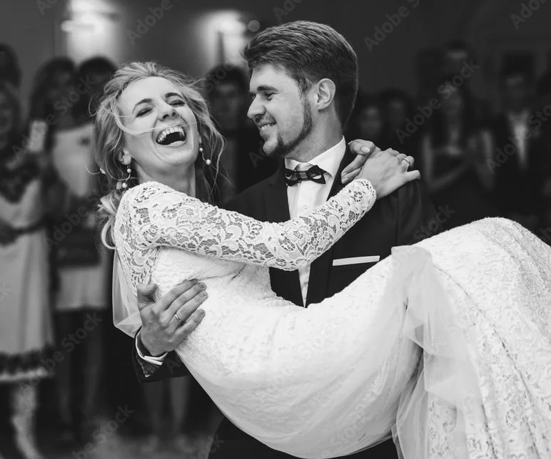 Black and white photo of a joyful bride and groom dancing at their wedding reception, with the groom holding the bride in his arms.  Keepsake & Co. Events Wedding Planner made their wedding a dream come true.