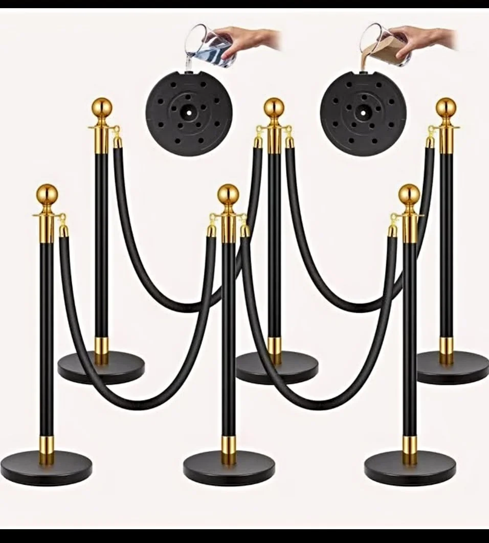 Stanchions with black ropes and gold accents, used for crowd control, with a person pouring water into a black circular base.