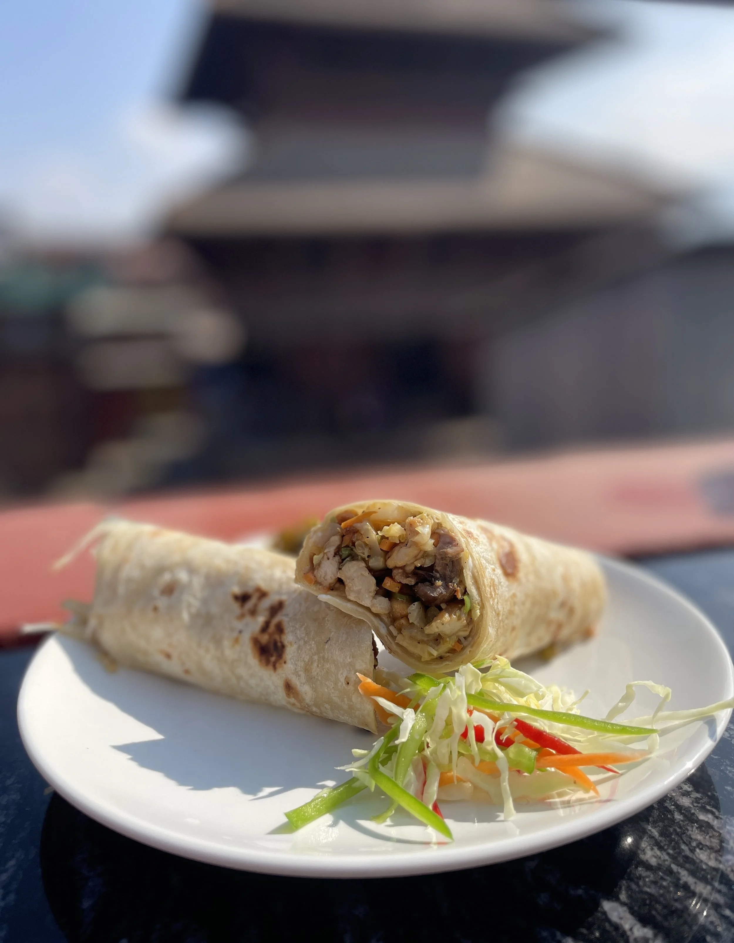 A freshly prepared wrap served with crisp slaw on the rooftop — simple, satisfying food enjoyed with open air and temple views.