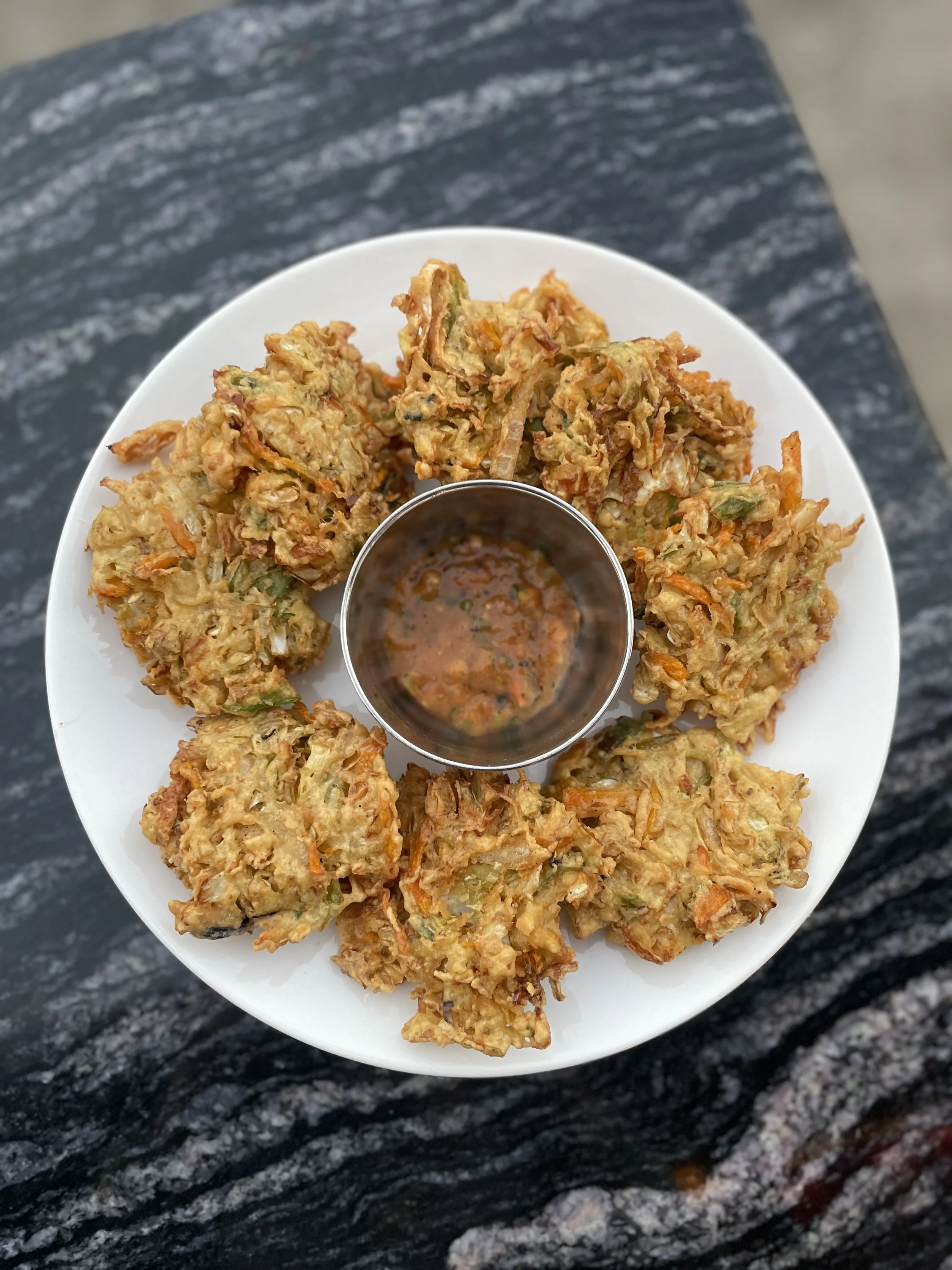 Golden vegetable pakora, lightly crisp and freshly fried, served with a house-made dipping sauce. A simple, familiar snack — best enjoyed slowly, one bite at a time.