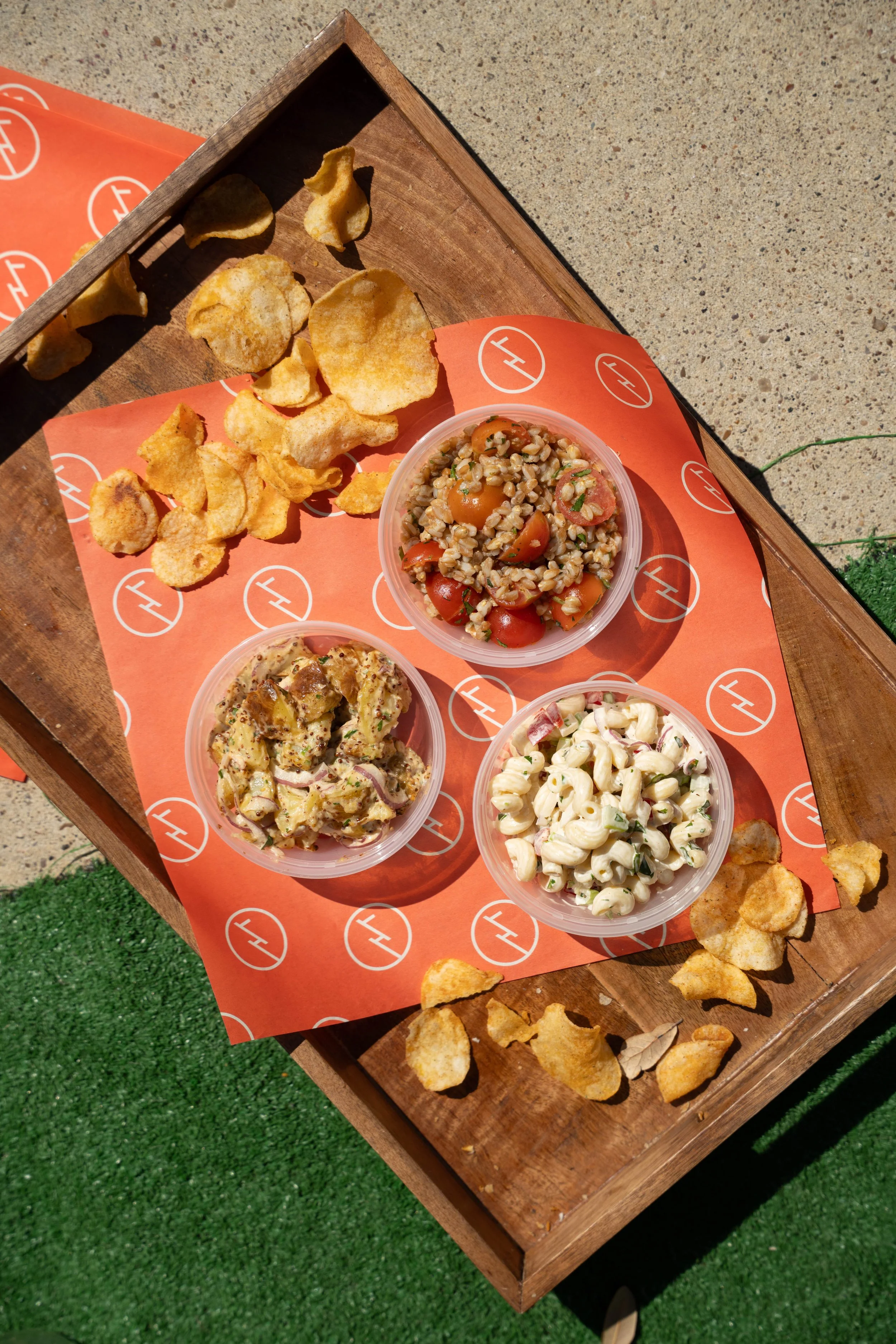 Side dishes in small plastic bowls on classic House Party branded paper