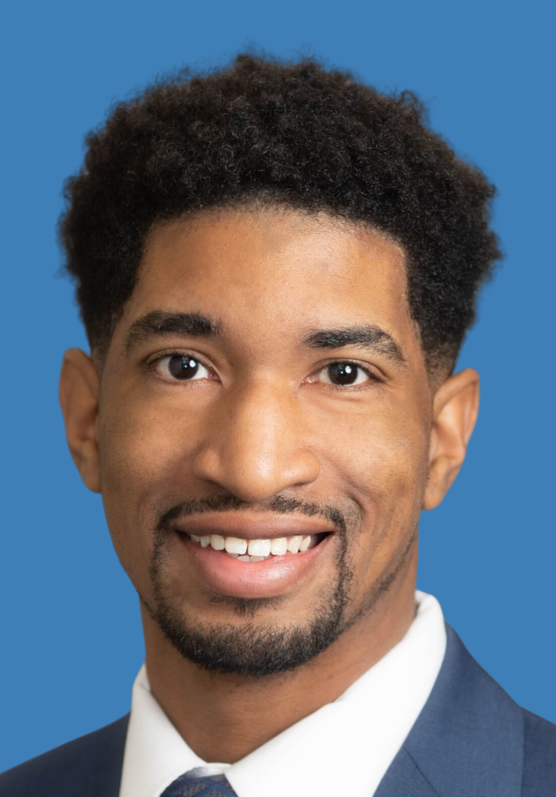 Smiling woman with curly hair, wearing glasses, earrings, and a striped top, inside a well-lit room.