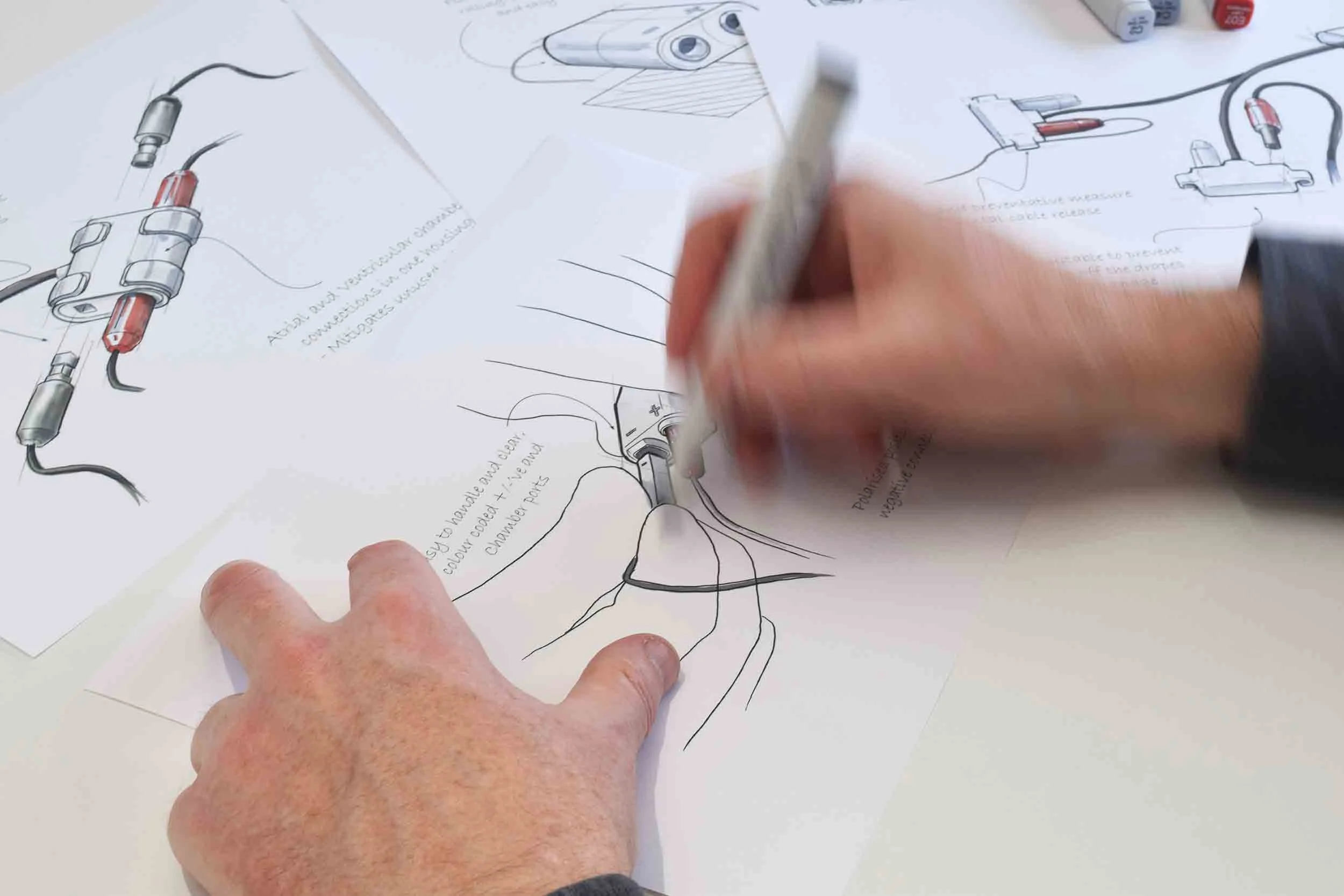 Hands sketching and annotating technical diagrams of electrical components on paper.