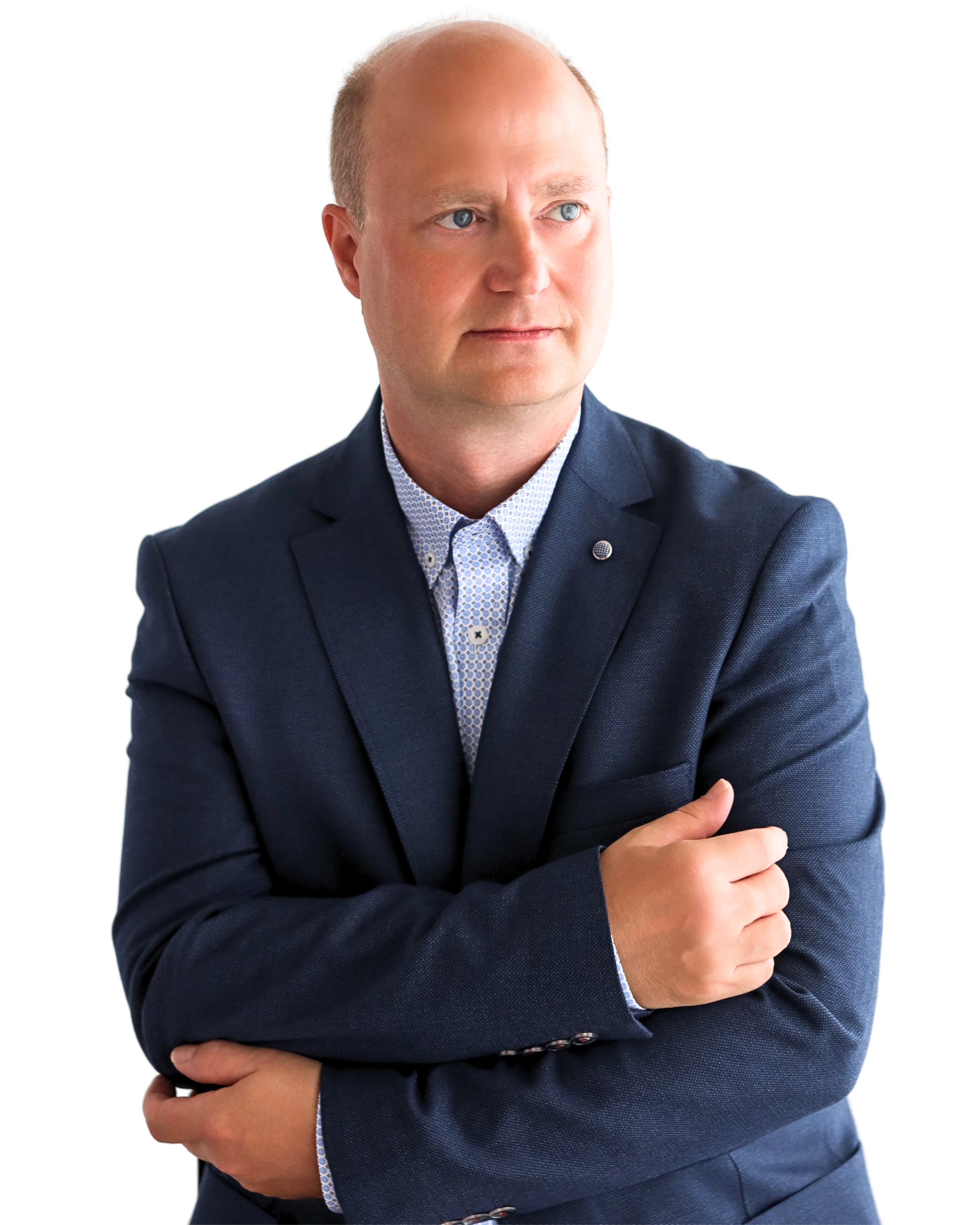 Ein Mann mit blonden Haaren in einem blauen Anzug und einer weißen Hemd trägt, wirkt nachdenklich und schaut nach rechts, mit verschränkten Armen.