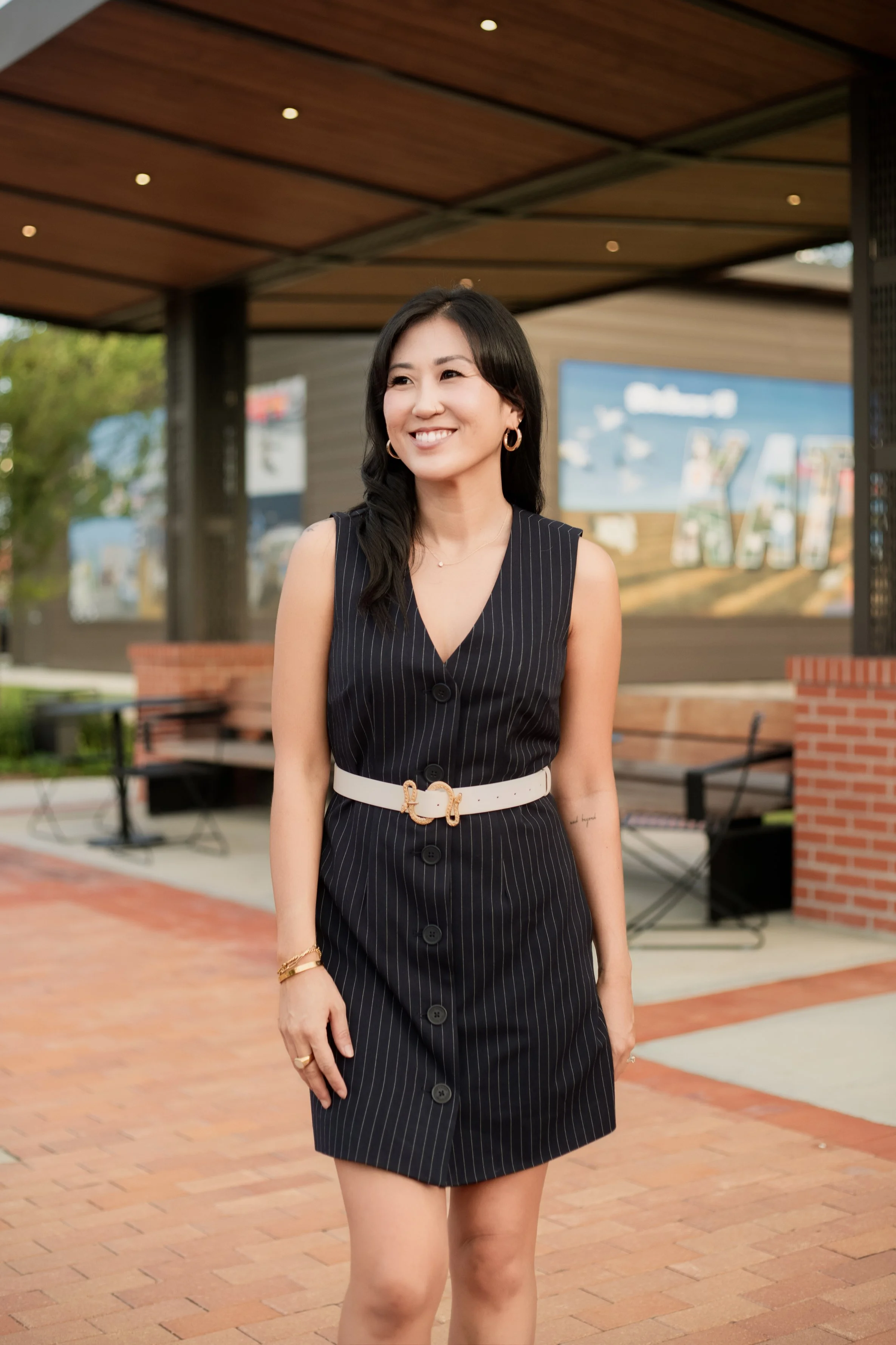 Personal branding portrait featuring a professional woman walking in a modern outdoor shopping district with warm natural light. Lifestyle business photography by Dominic Alvarez Photography serving Houston, Katy, and surrounding areas across Southea
