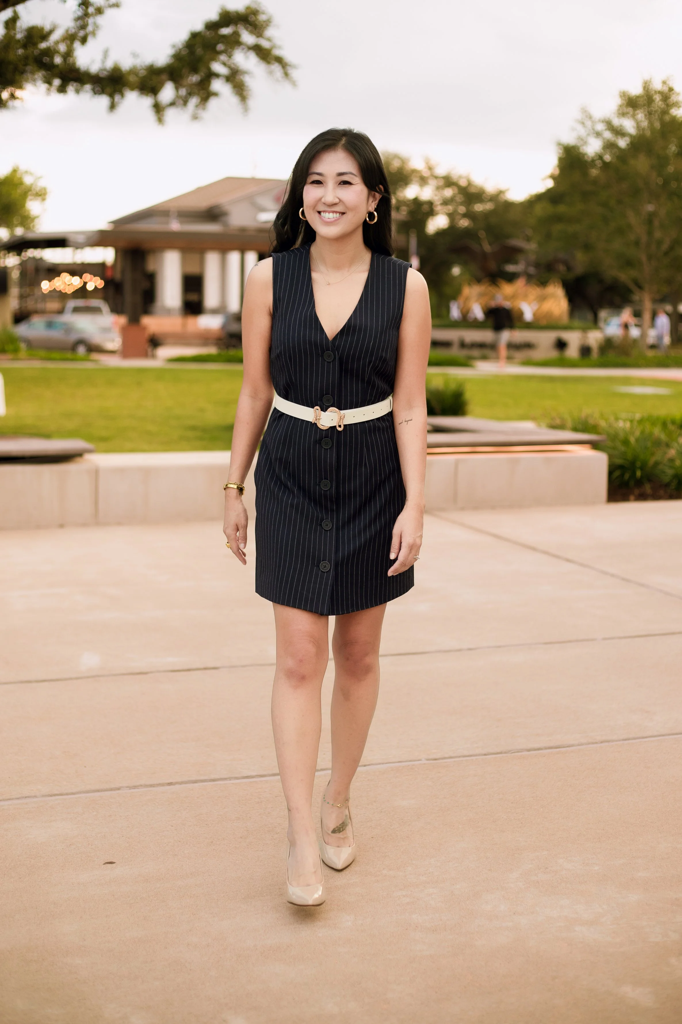 Lifestyle personal branding portrait of a professional woman walking through a modern outdoor plaza in soft evening light. Business branding photography by Dominic Alvarez Photography serving Houston, Katy, and surrounding areas.
