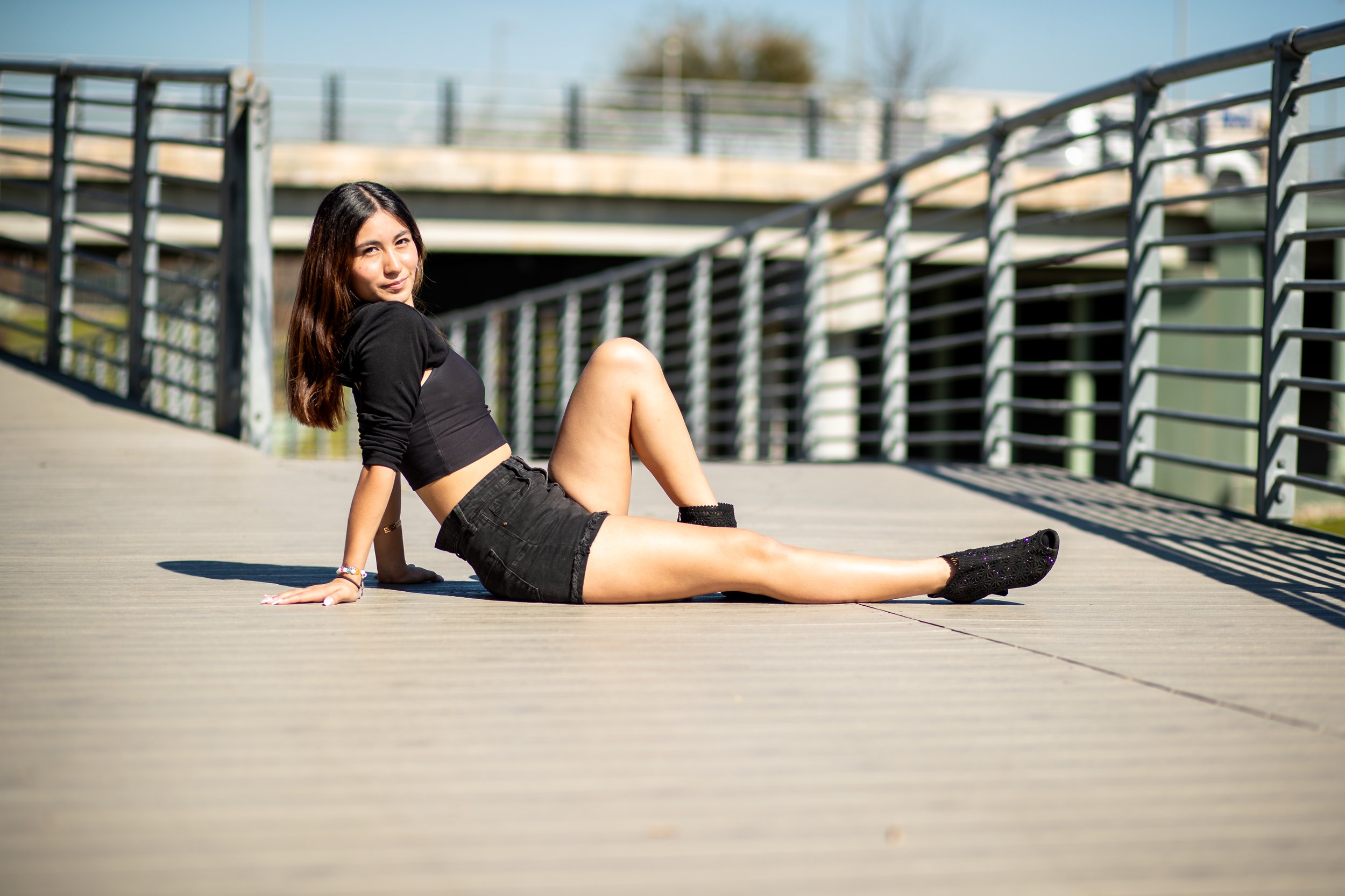 High school senior girl posing confidently on a modern bridge in Katy, Texas during an outdoor senior portrait session by Dominic Alvarez Photography.