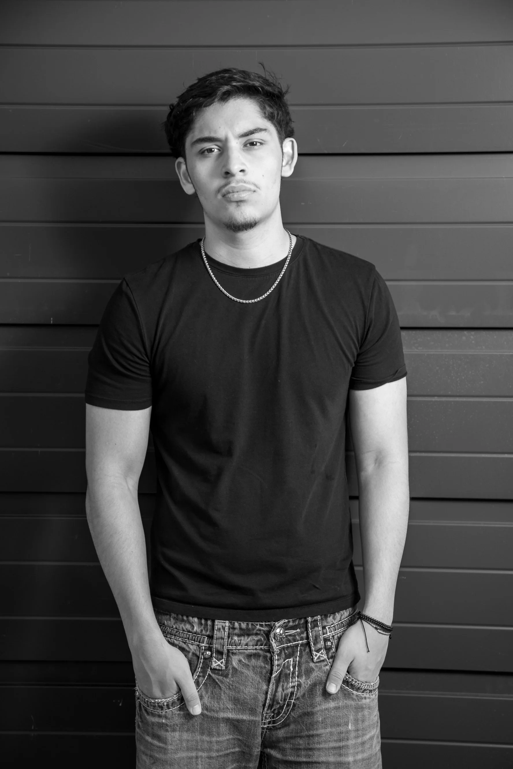 Black and white high school senior portrait featuring a male senior in a relaxed, modern pose against an urban backdrop. Timeless, clean senior photography by Dominic Alvarez Photography serving Houston, Katy, and surrounding areas across Southeast T