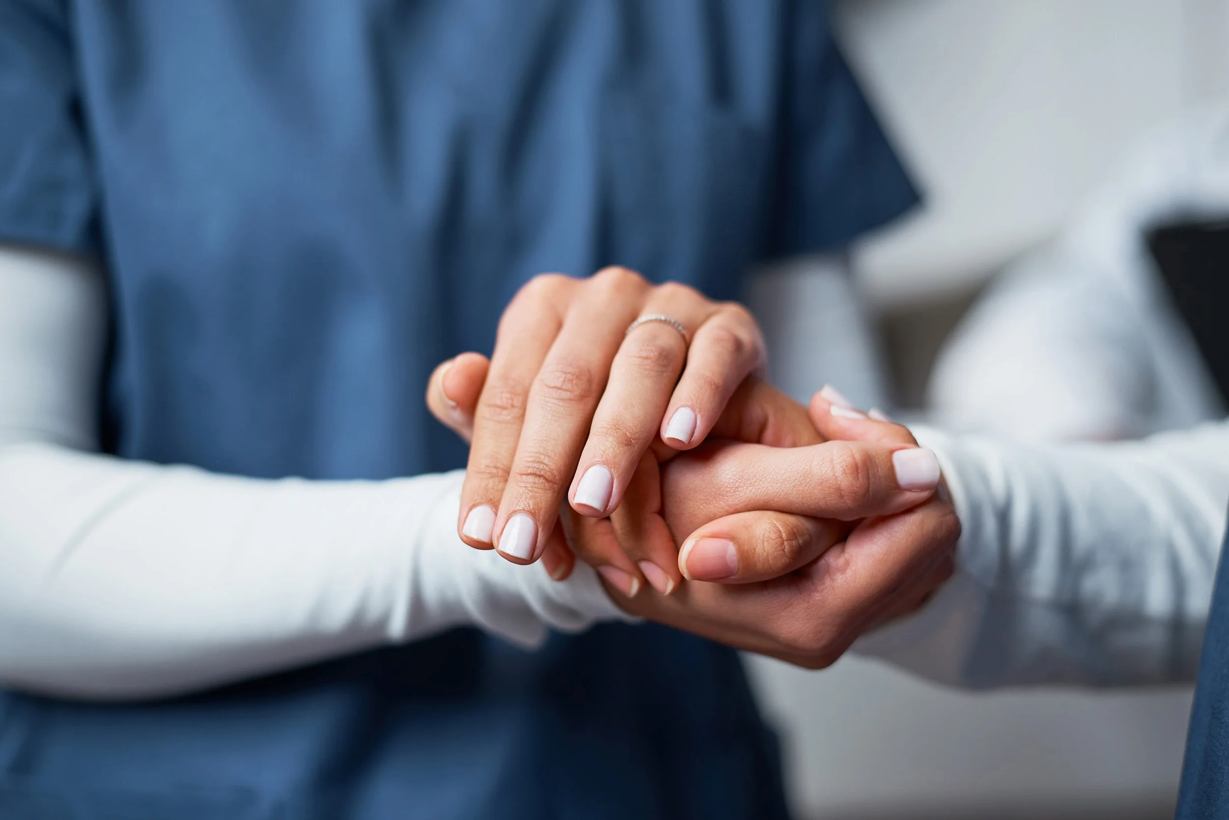 Close-up of a couple holding hands, the woman wearing a ring on her finger, symbolizing an engagement or wedding.