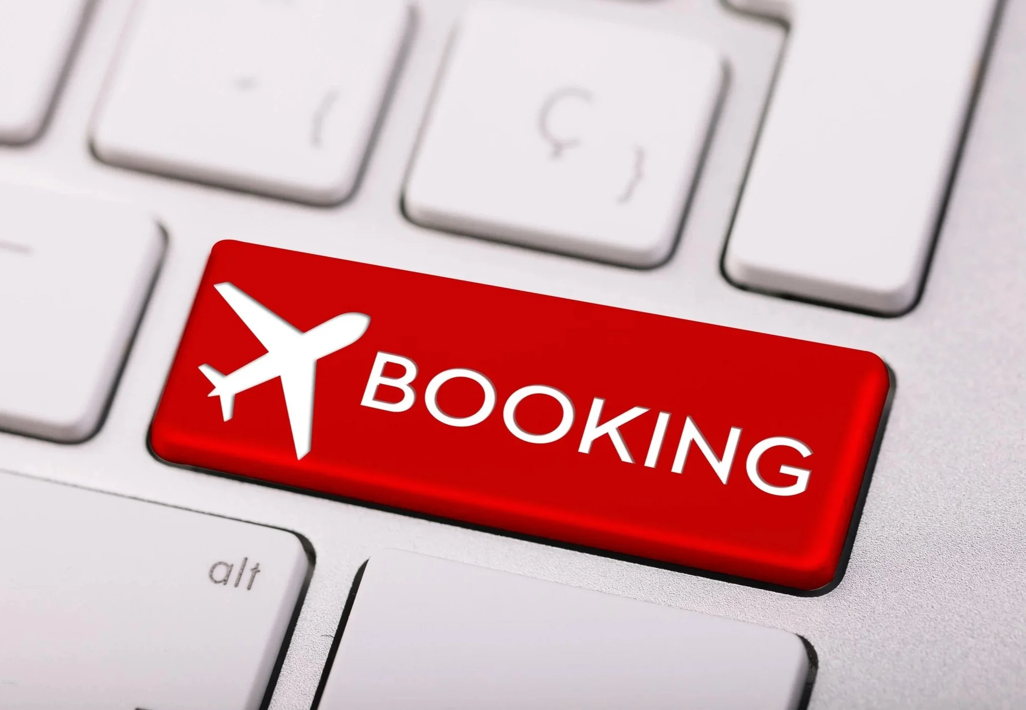 A computer keyboard with a red key labeled 'BOOKING' and an airplane icon.