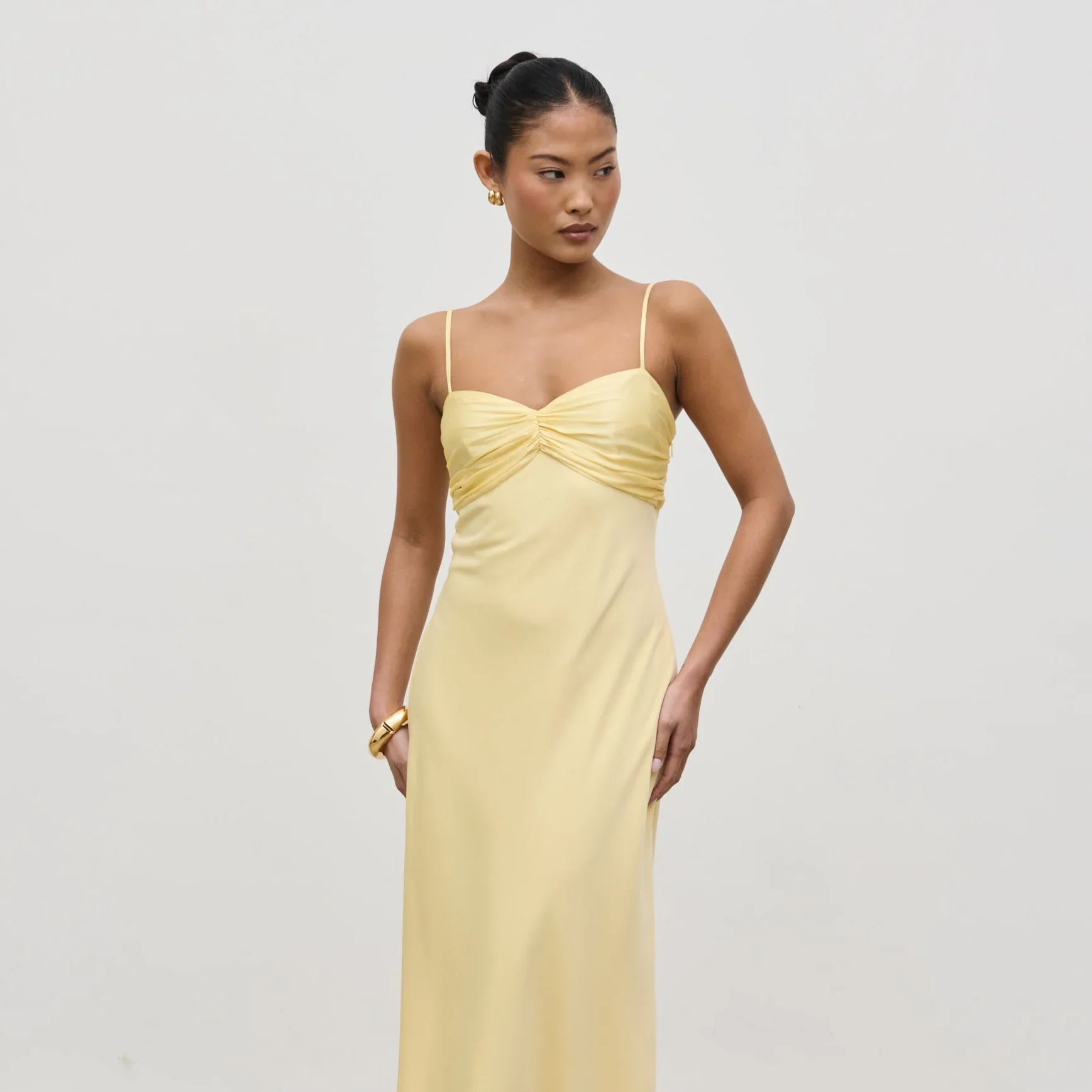 A middle-aged man with gray beard sitting on a beige bench in a simple room with neutral-colored walls, looking thoughtfully into the distance.