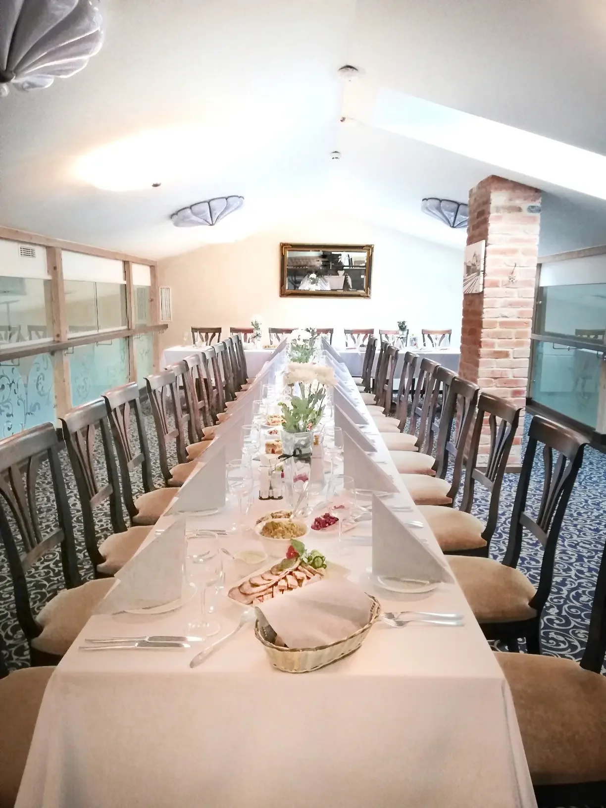 Ilgas banketinis stalas su maistu ir taurėmis, paruoštas šventei restorane „XIX amžius“.