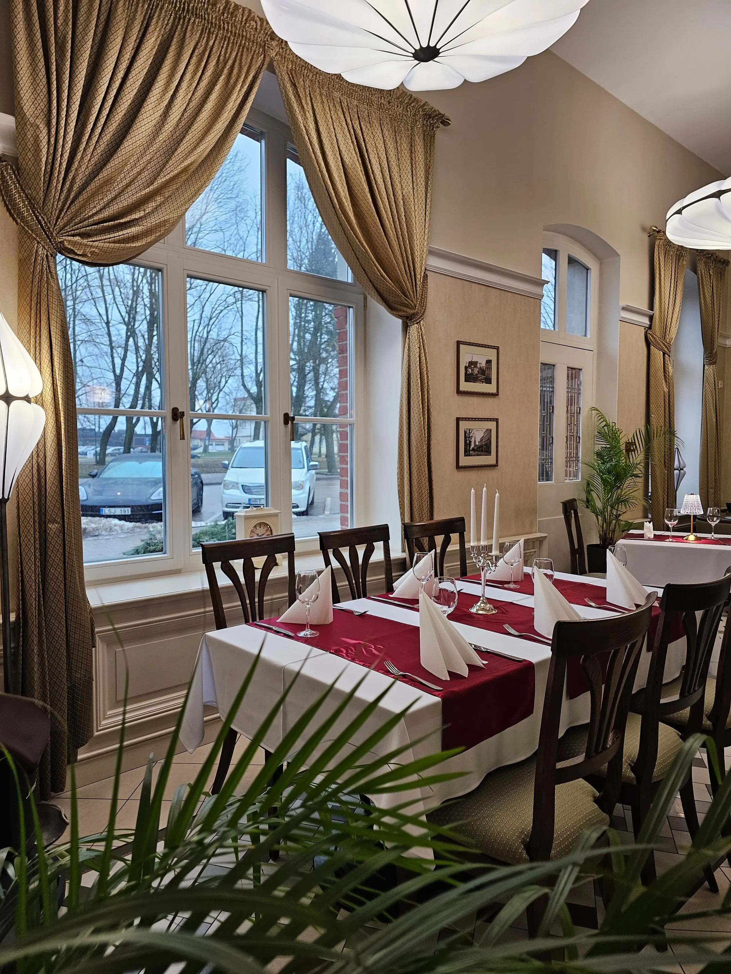 Iškilmingas stalo serviravimas su bordo spalvos detalėmis ir žvakidėmis restorane Klaipėdoje.