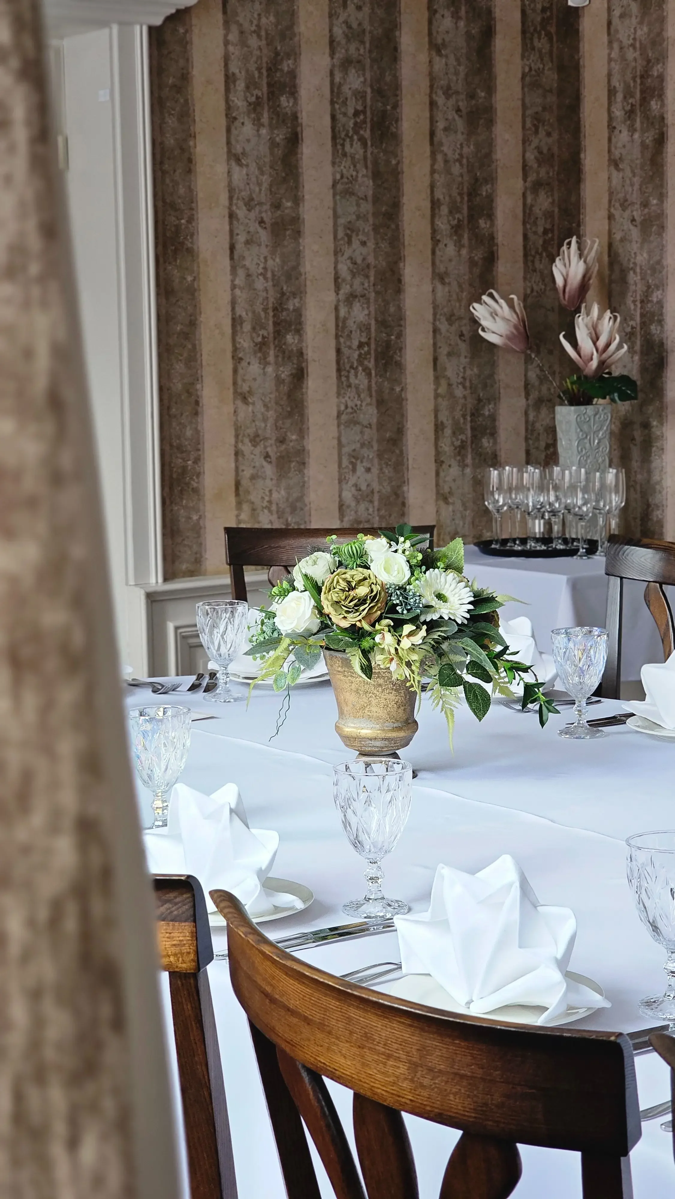 Elegantiška stalo serviruotė su baltomis gėlėmis šventiniam banketui restorane.