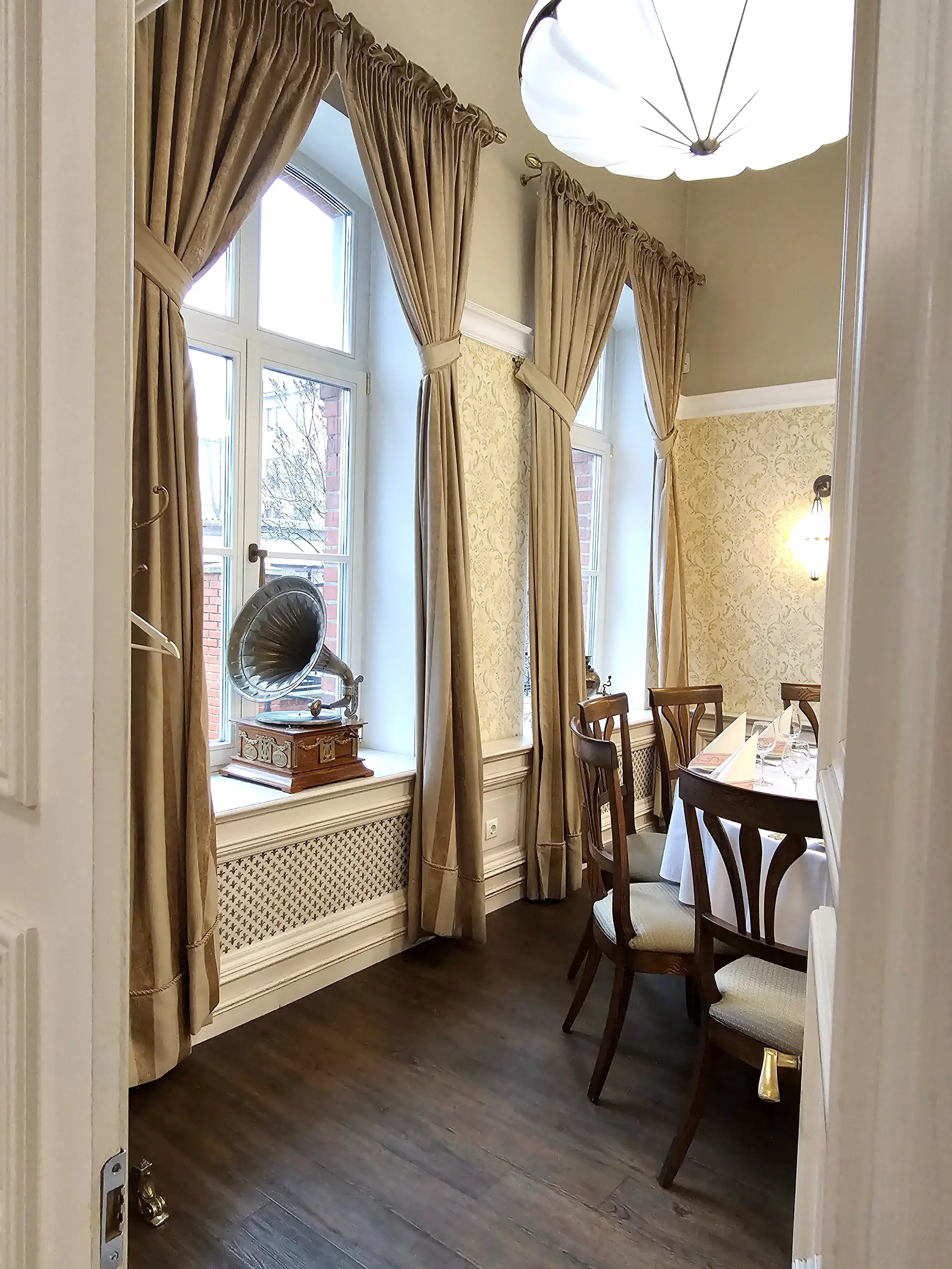 Jaukus restorano kampelis su paserviruotu stalu ir antikvariniu gramofonu ant palangės.