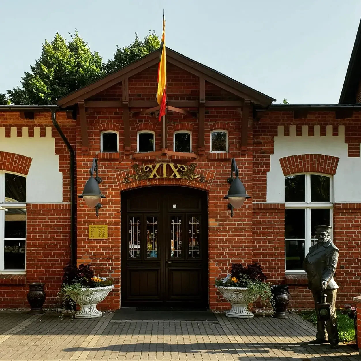 Pagrindinis įėjimas į restoraną „XIX amžius“ Klaipėdoje su bronzine stoties budėtojo skulptūra.