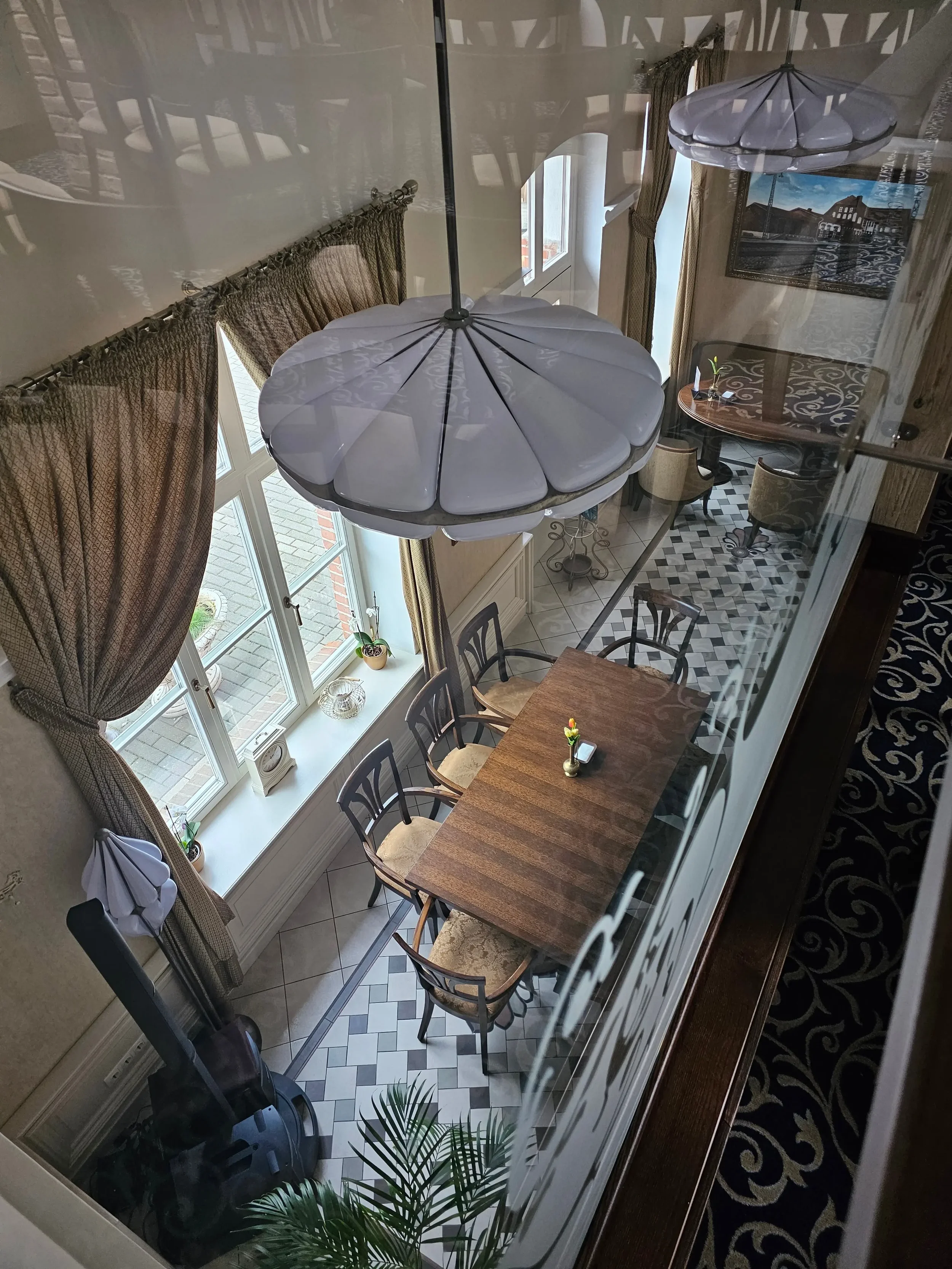 Elegantiška restorano erdvė iš viršaus su mediniu stalu ir dekoratyviniu apšvietimu.