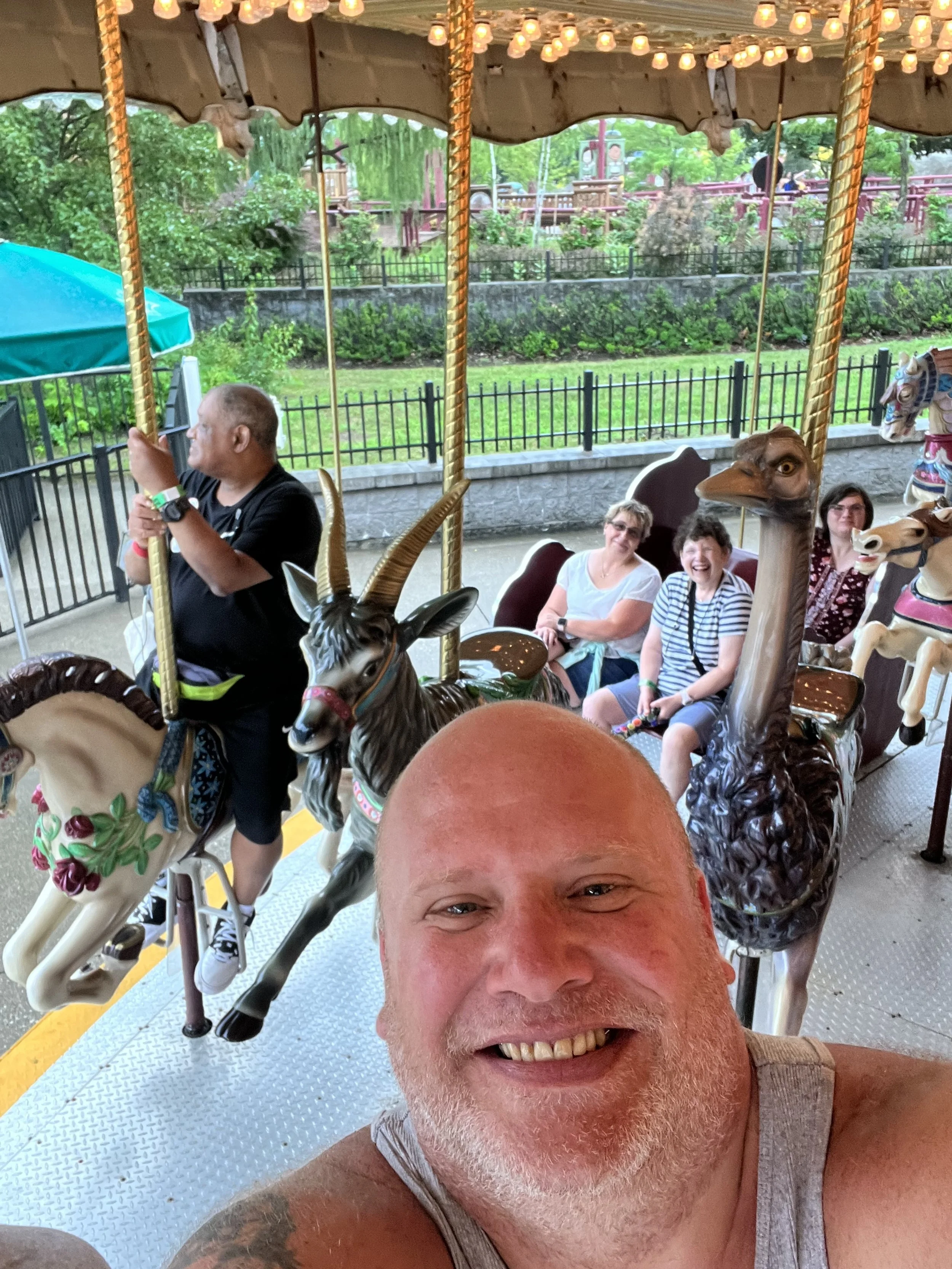 A group of people riding a carousel with animal-shaped and mythical creature rides, smiling and enjoying the ride