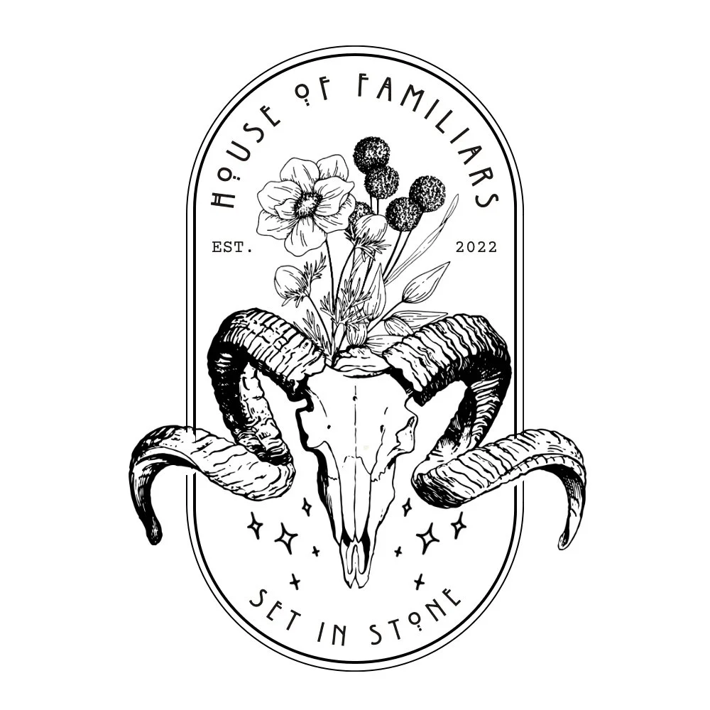 A botanical illustration featuring a skull with ram horns and flowers growing from it, framed by an oval border with text.