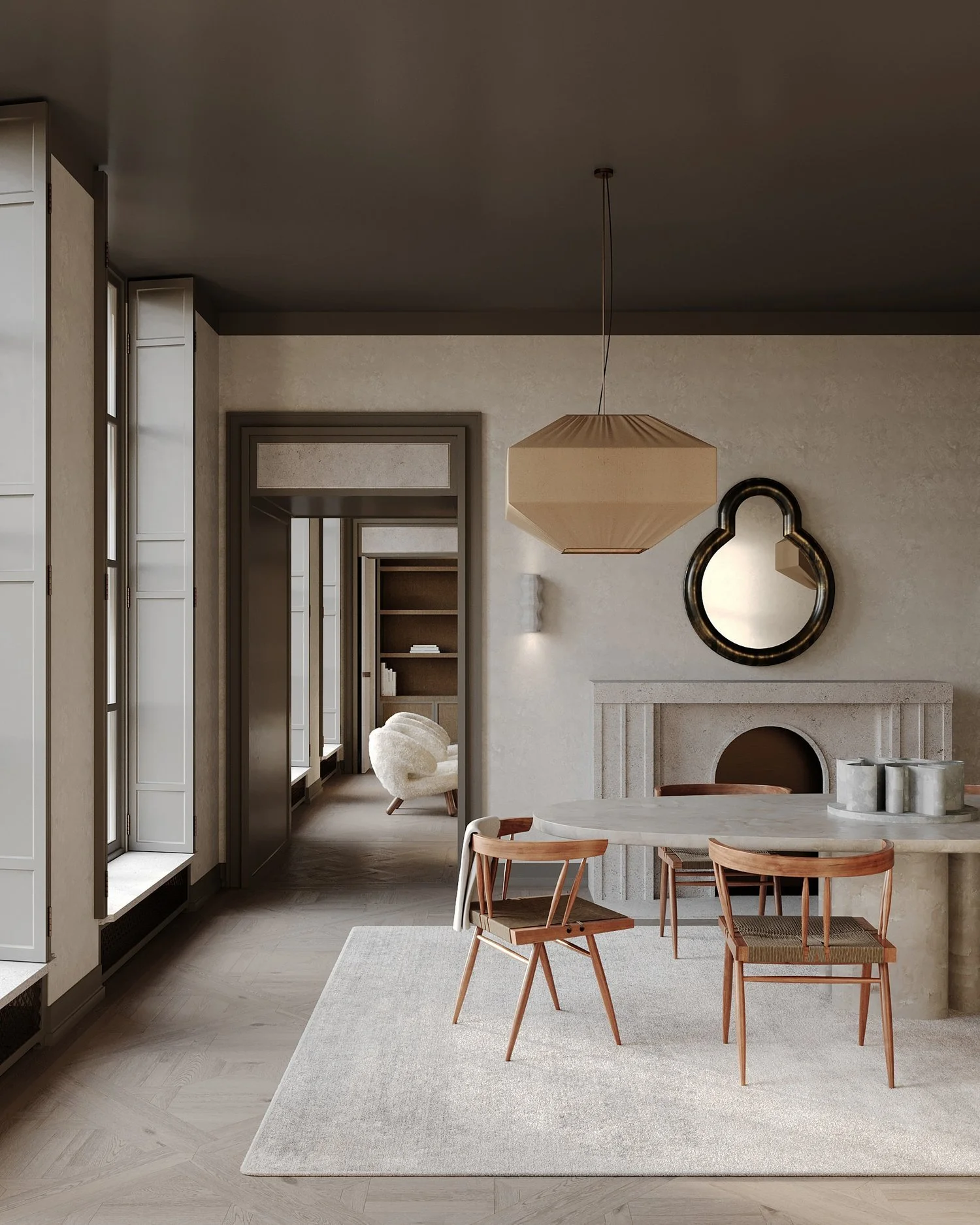 A modern dining room with a round white table, four wooden chairs, a decorative mirror on the wall, a beige fireplace, and a beige geometric pendant light. In the background, a hallway with a white armchair and built-in shelves is visible.