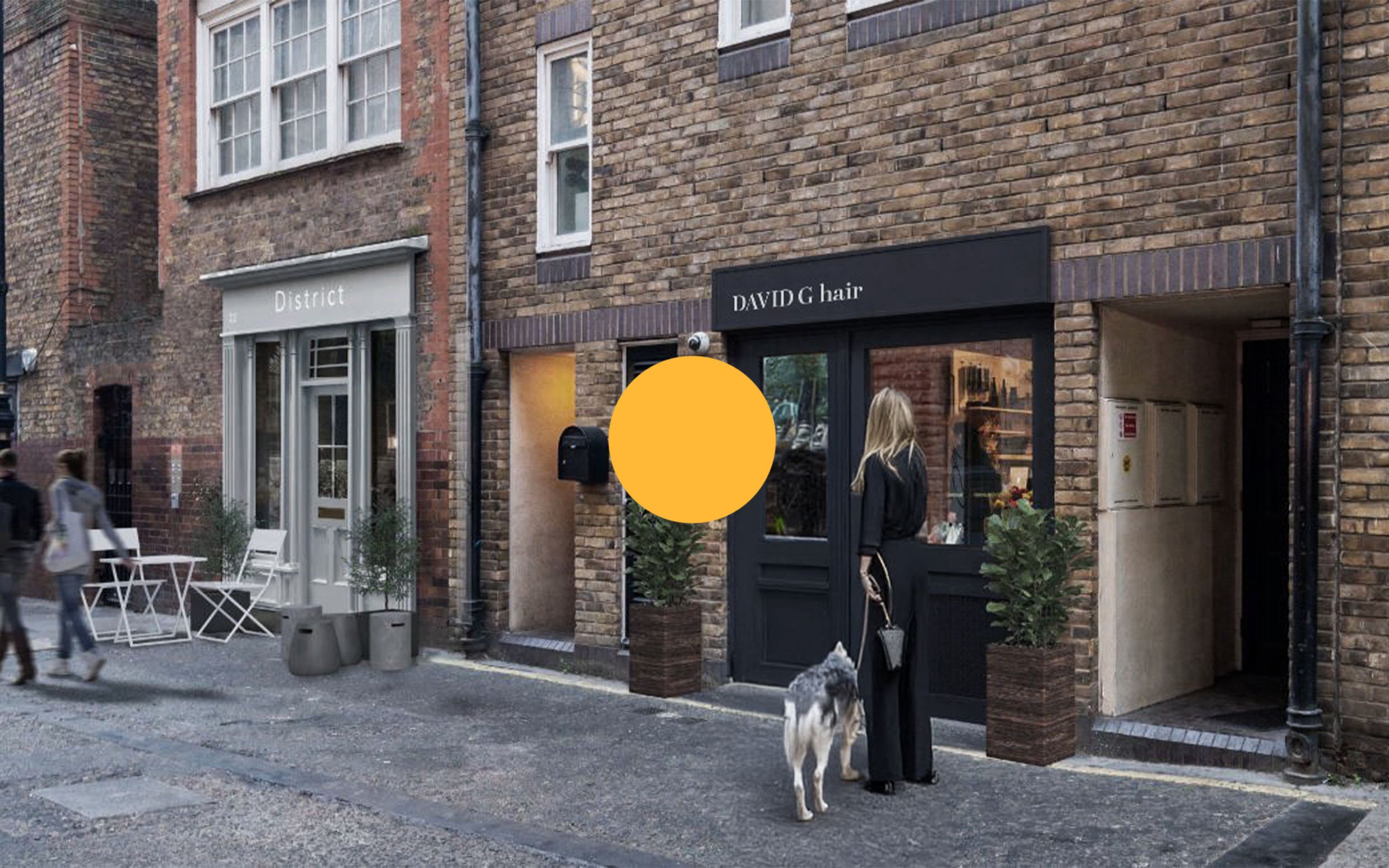 Street scene with brick buildings, a woman walking her dog, and a storefront named DAVID G hair.