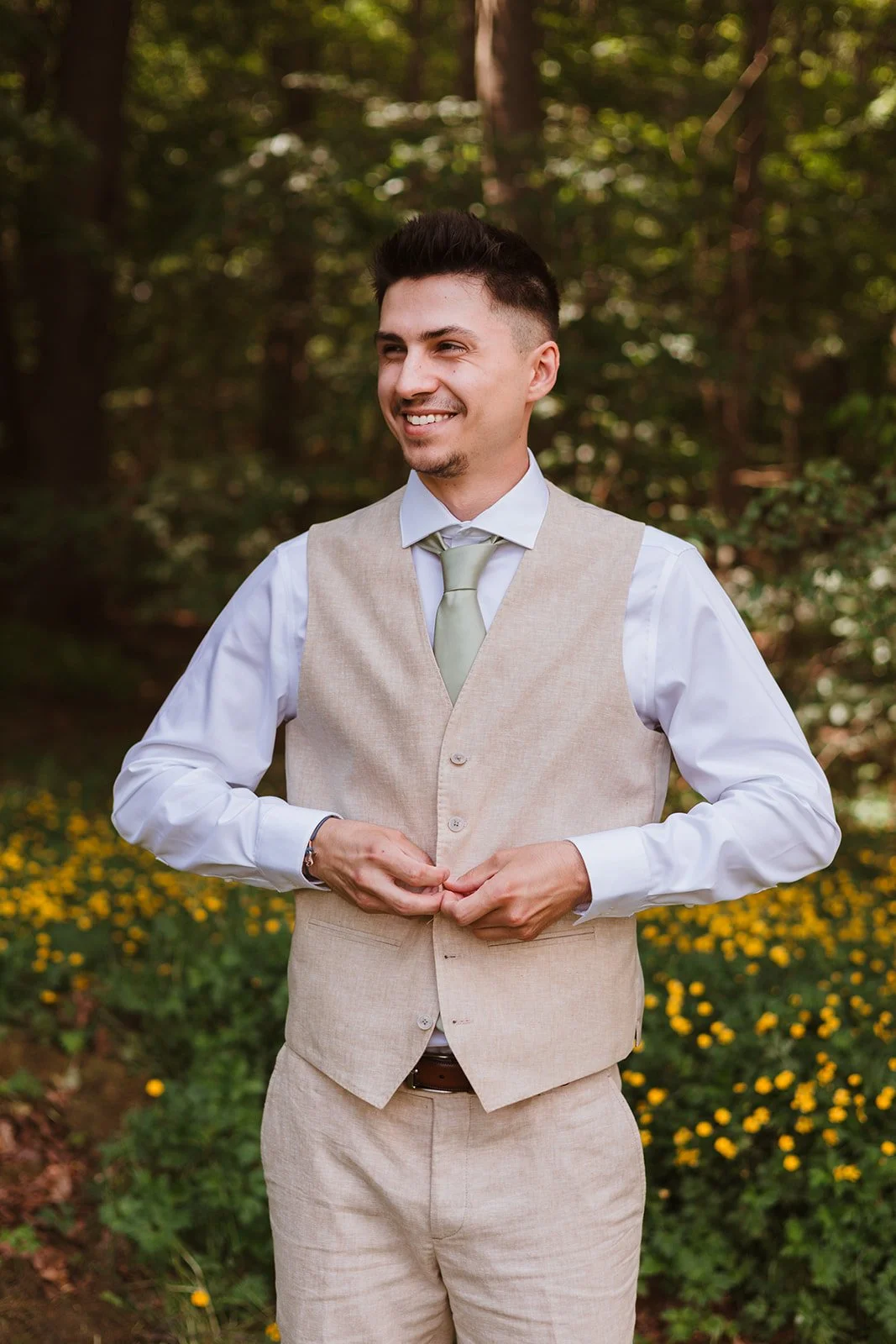 Groom buttons vest in the backyard before their wedding.
