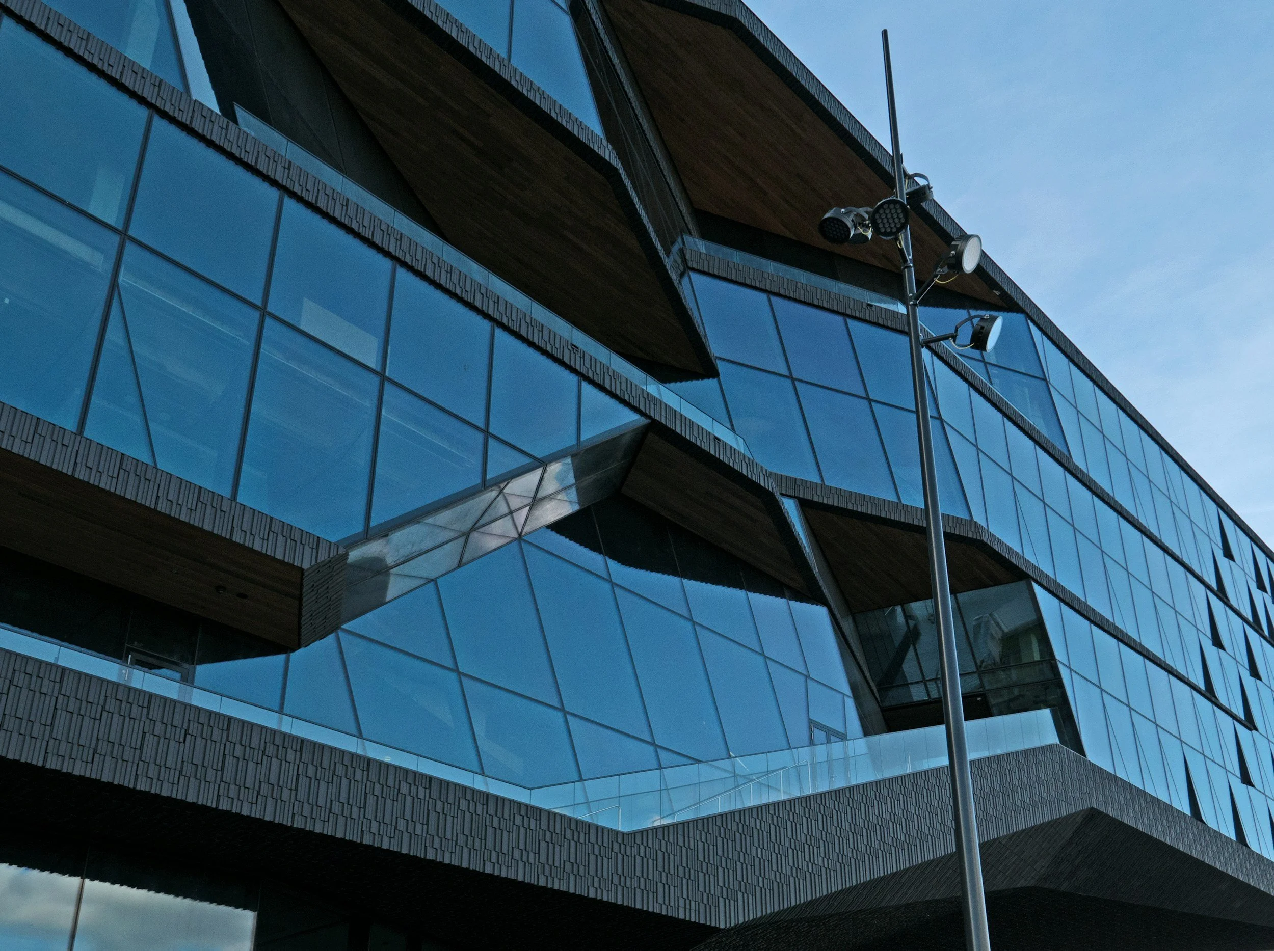 Modern building with large glass windows and wooden accents, with a street light in the foreground.
