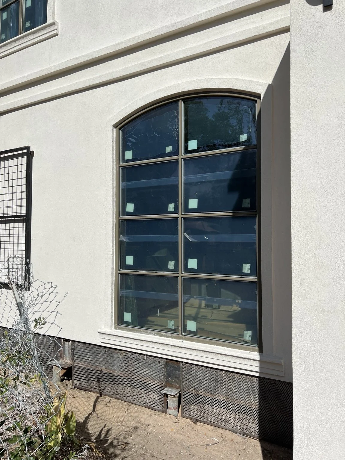Arched metal-framed window with eight glazed sections installed in an exterior wall.
