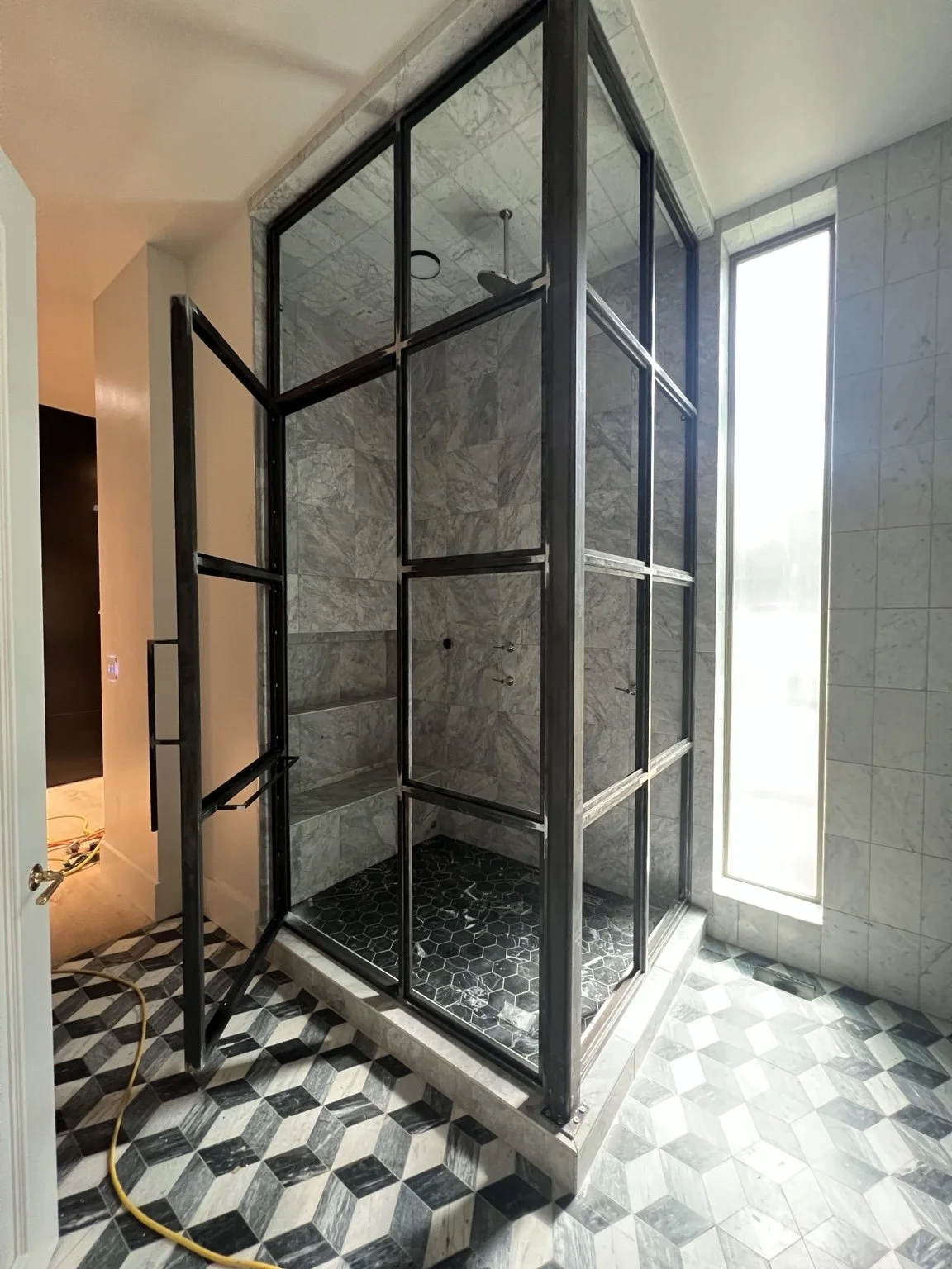 Tall metal-framed shower enclosure with rectangular divisions and an open hinged door.