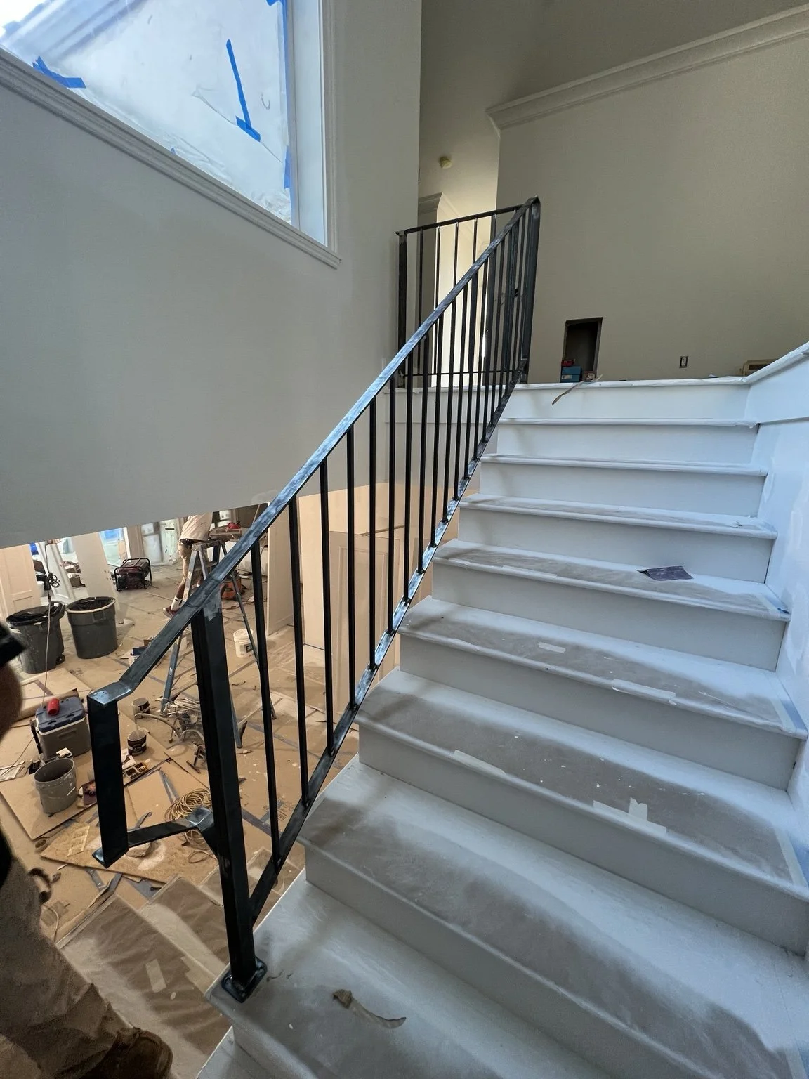 Metal handrail and vertical balusters installed along an interior staircase.