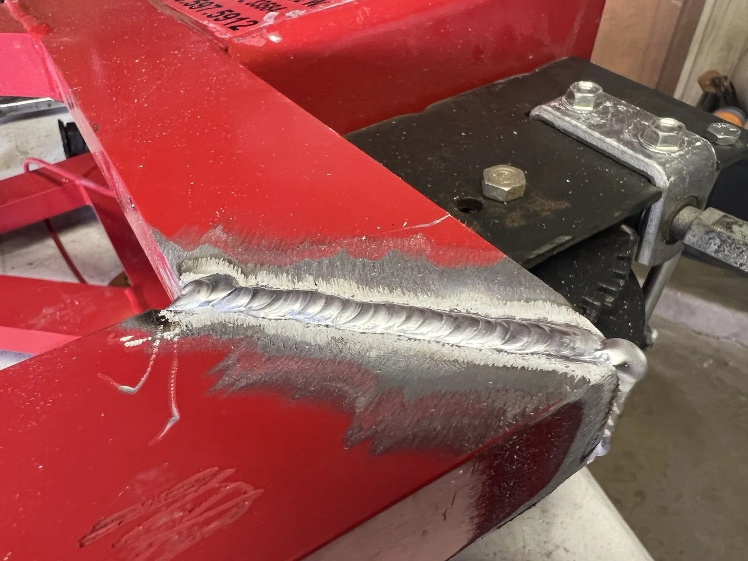 Close view of a weld joining red-painted equipment components.