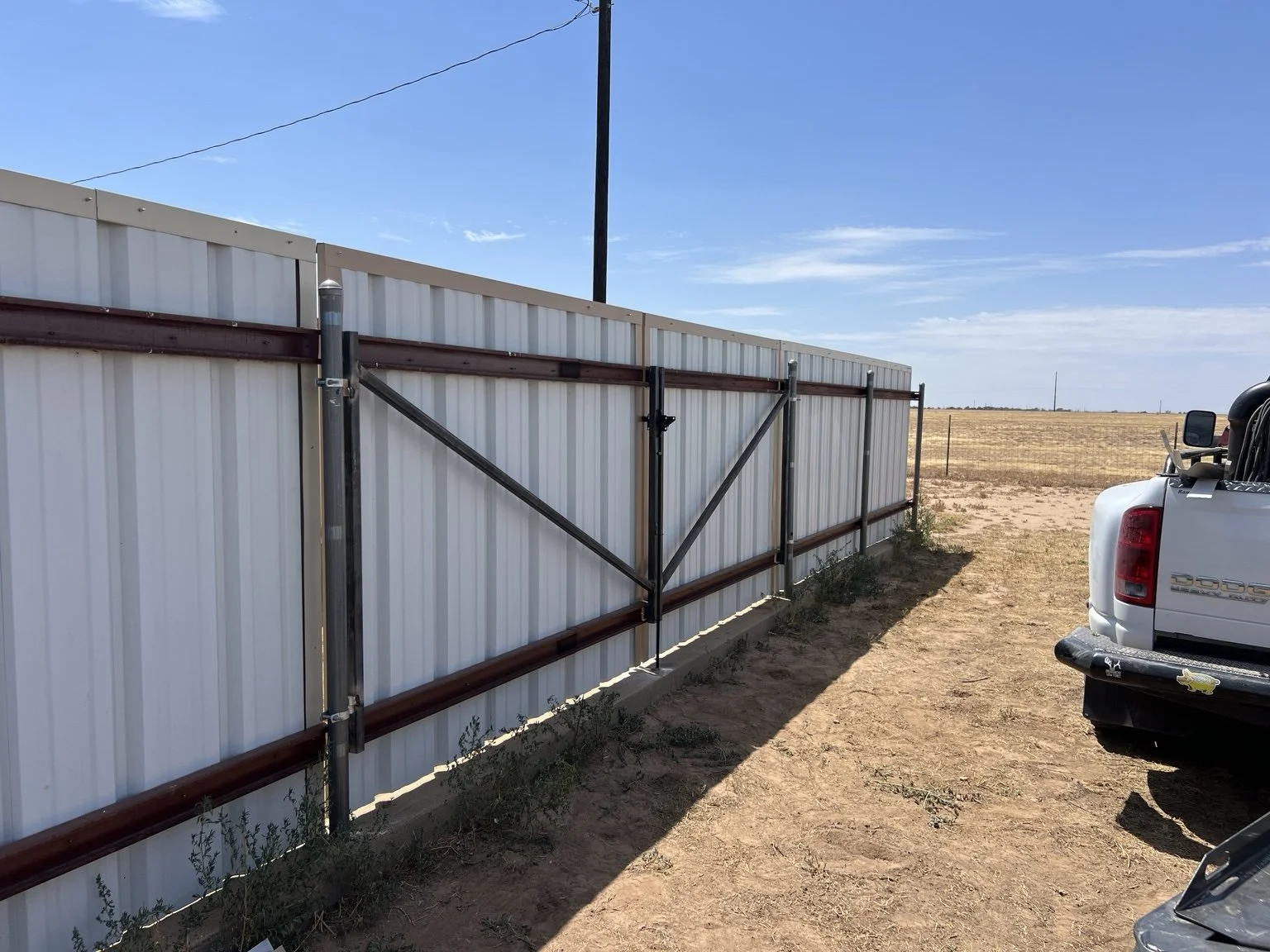Metal-framed double gate with diagonal braces and white privacy panels.