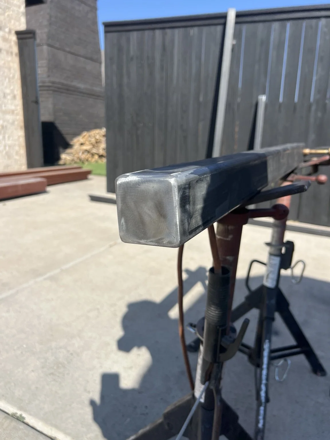 Smooth finished end cap on a rectangular metal tube held on fabrication stands.