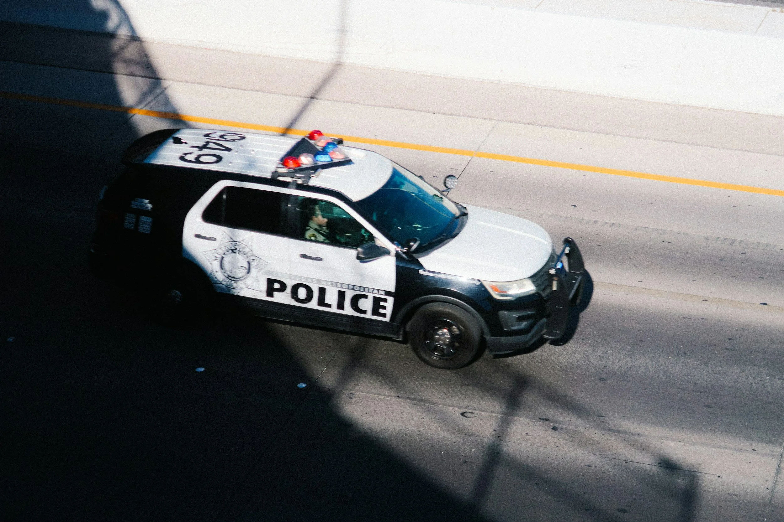 A police car drives down the road with a police officer seated in the back, showcasing law enforcement in action.