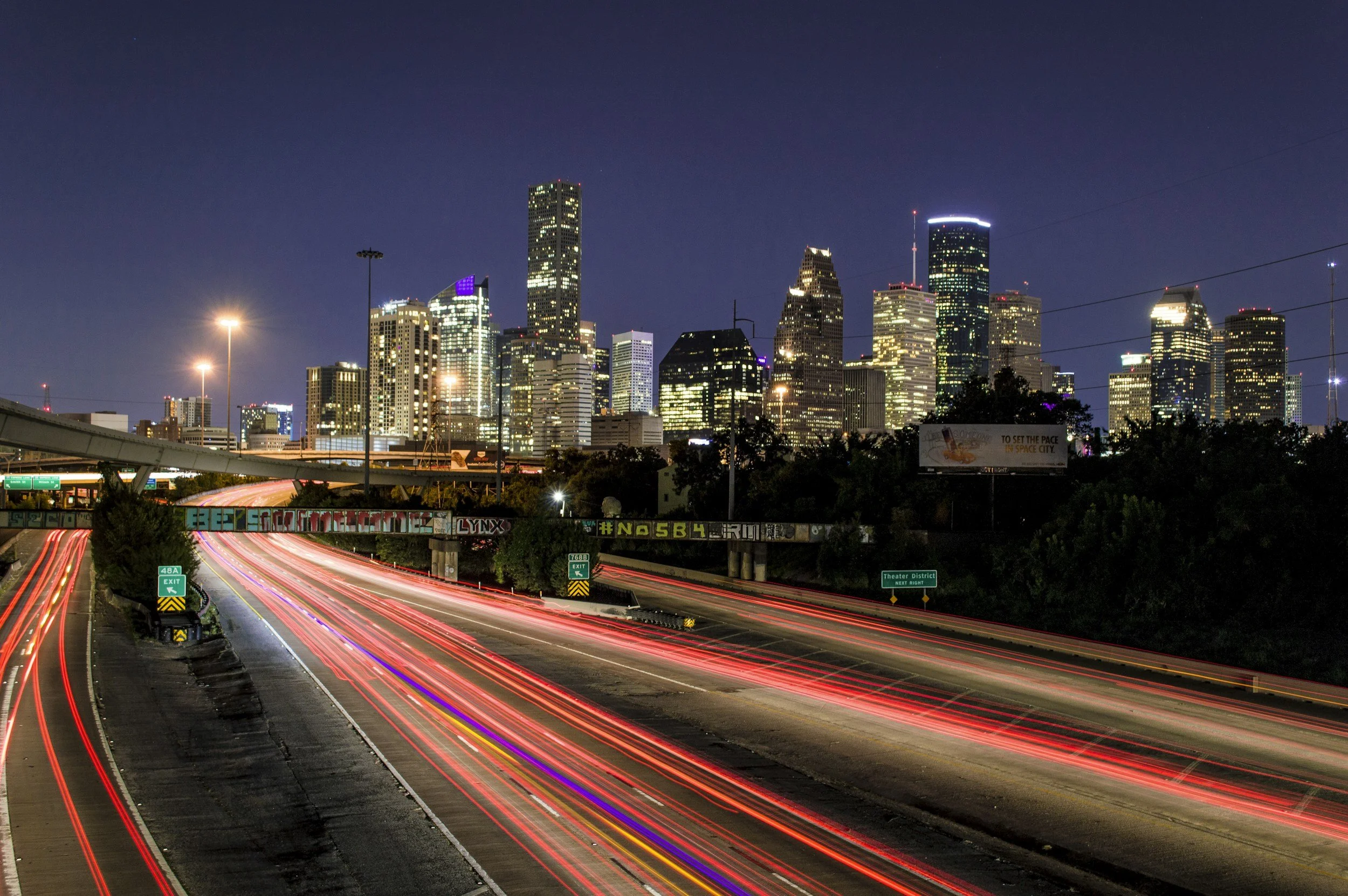 Houston skyline illuminated at night, showcasing tall buildings against a dark sky with scattered stars.