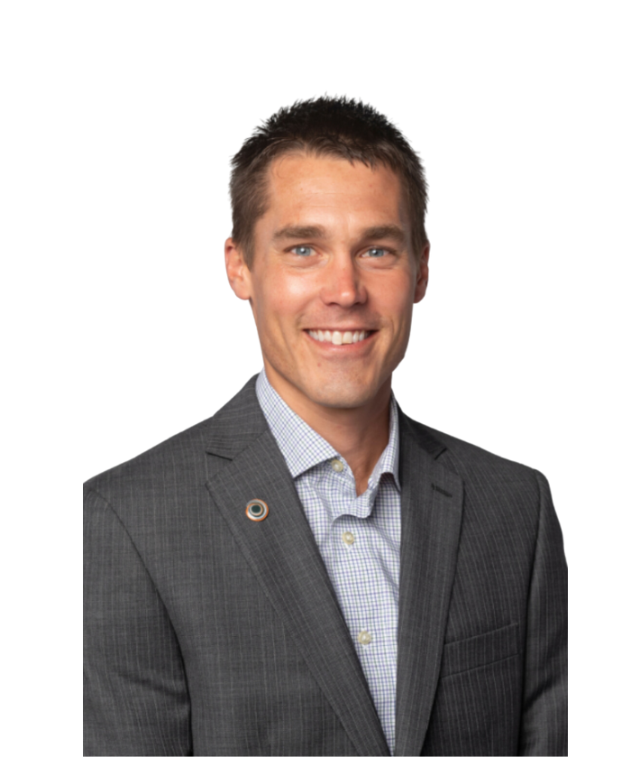 A smiling man in a gray business suit with a checkered shirt against a white background.