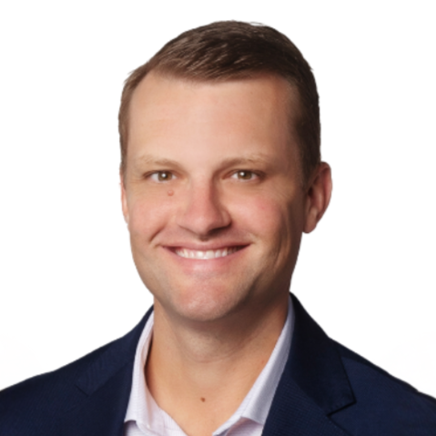 Headshot of a smiling man in a suit and white shirt against a white background.