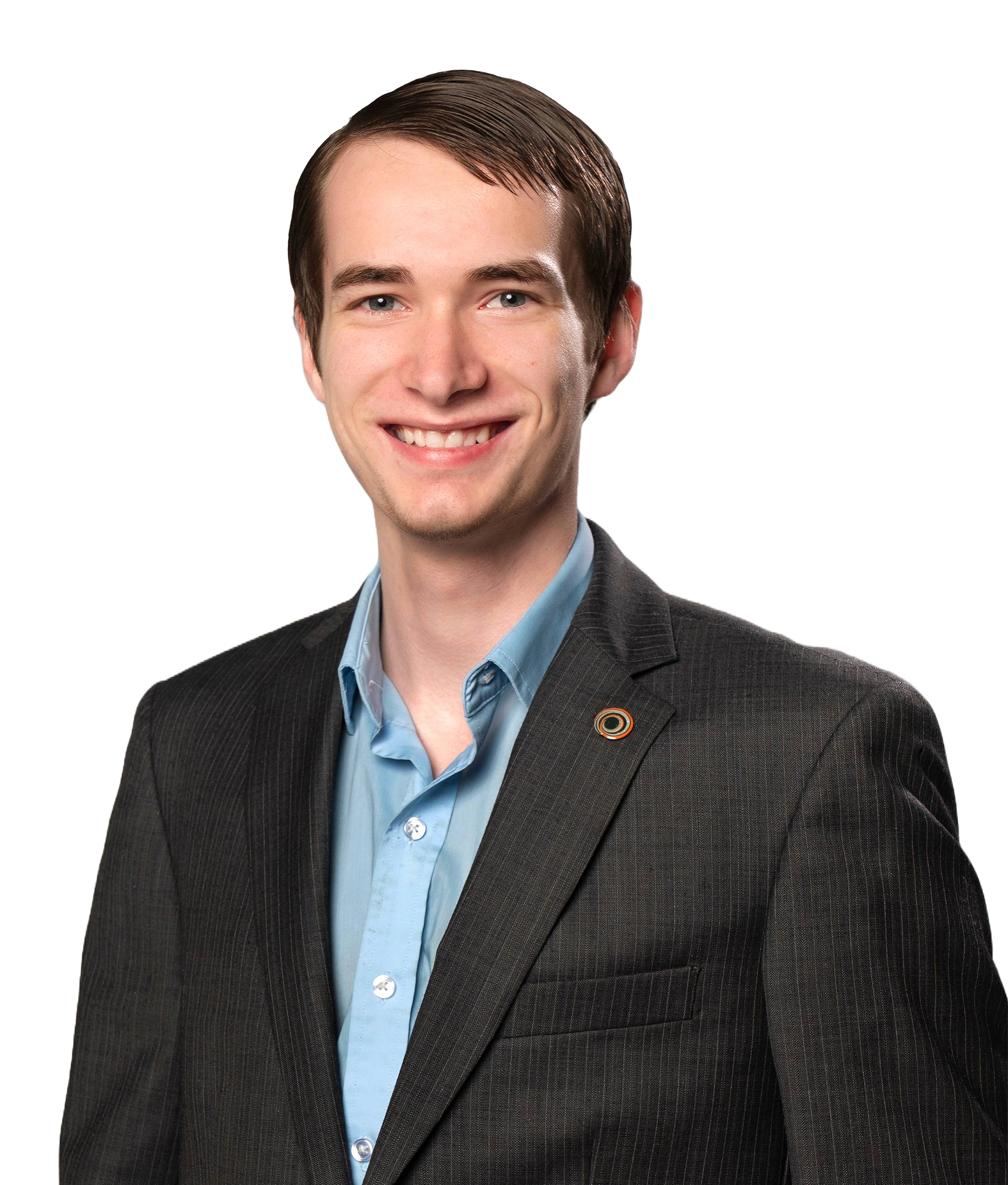 Portrait of a young man with short brown hair, smiling, dressed in a business suit with a light blue shirt, standing against a white background.