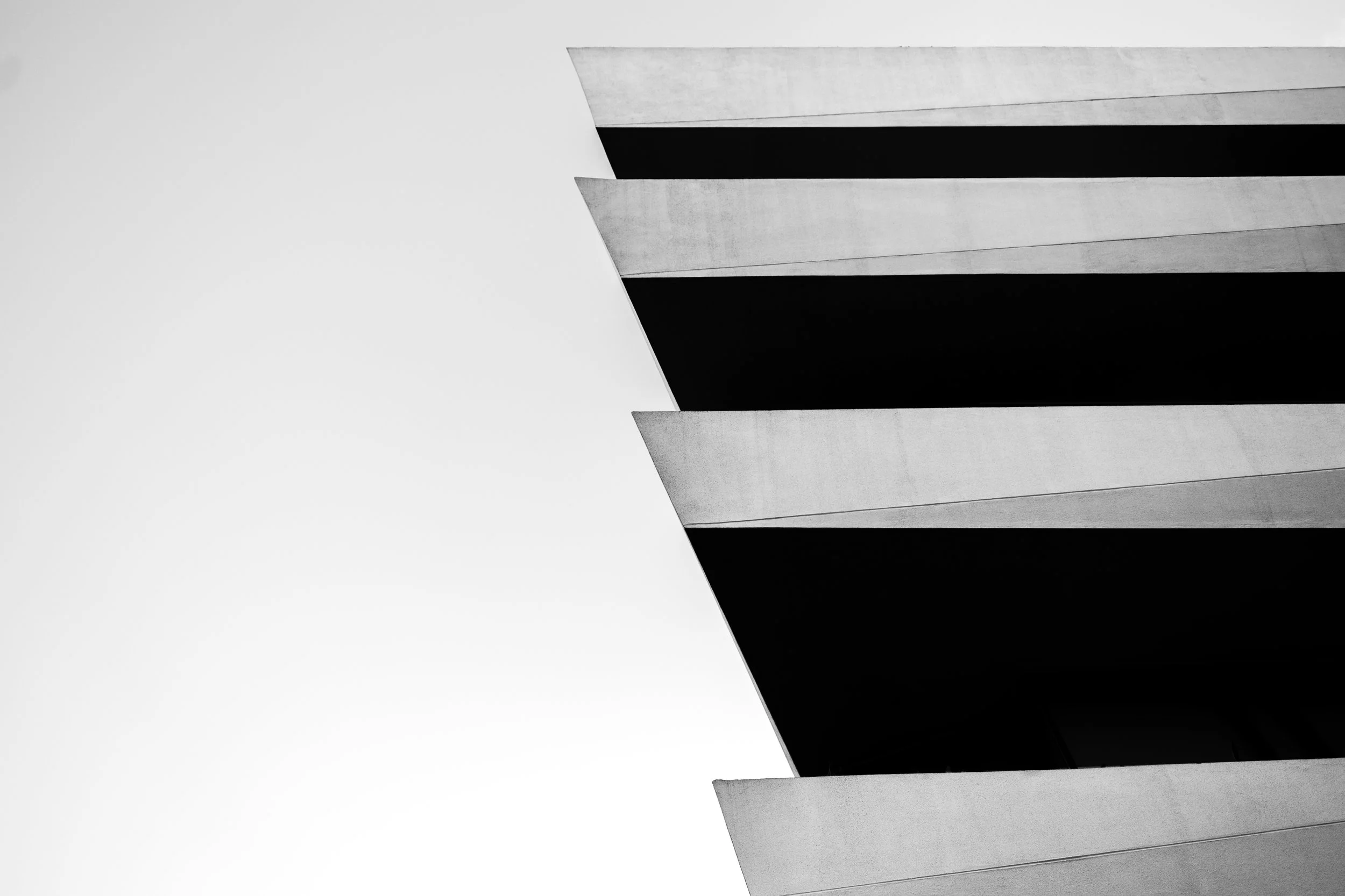 Detalle en blanco y negro de un edificio con fachadas inclinadas y ventanas oscuras.