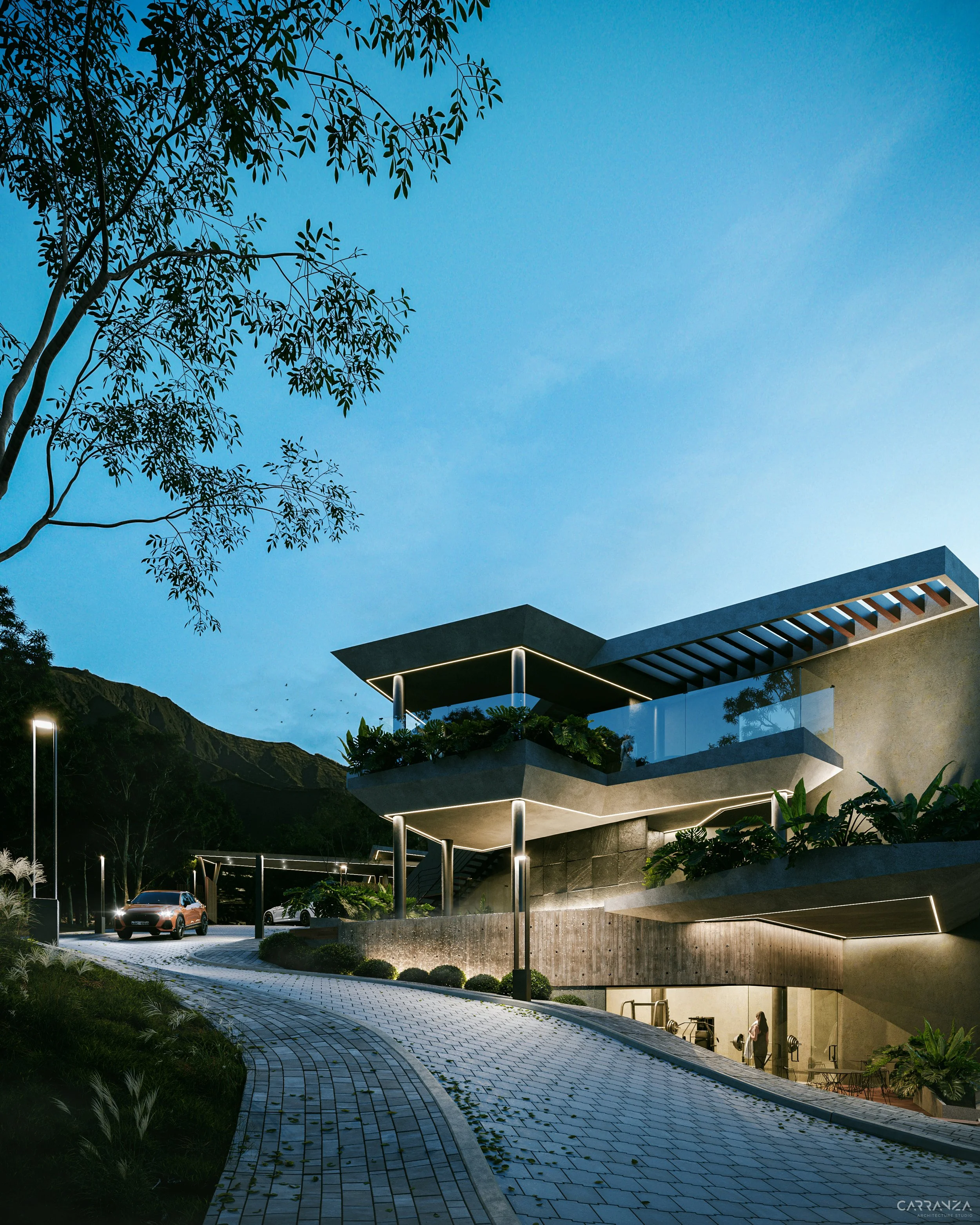 Vista nocturna de un moderno edificio residencial con terrazas y jardines, con iluminación exterior y autos estacionados en el camino adoquinado.
