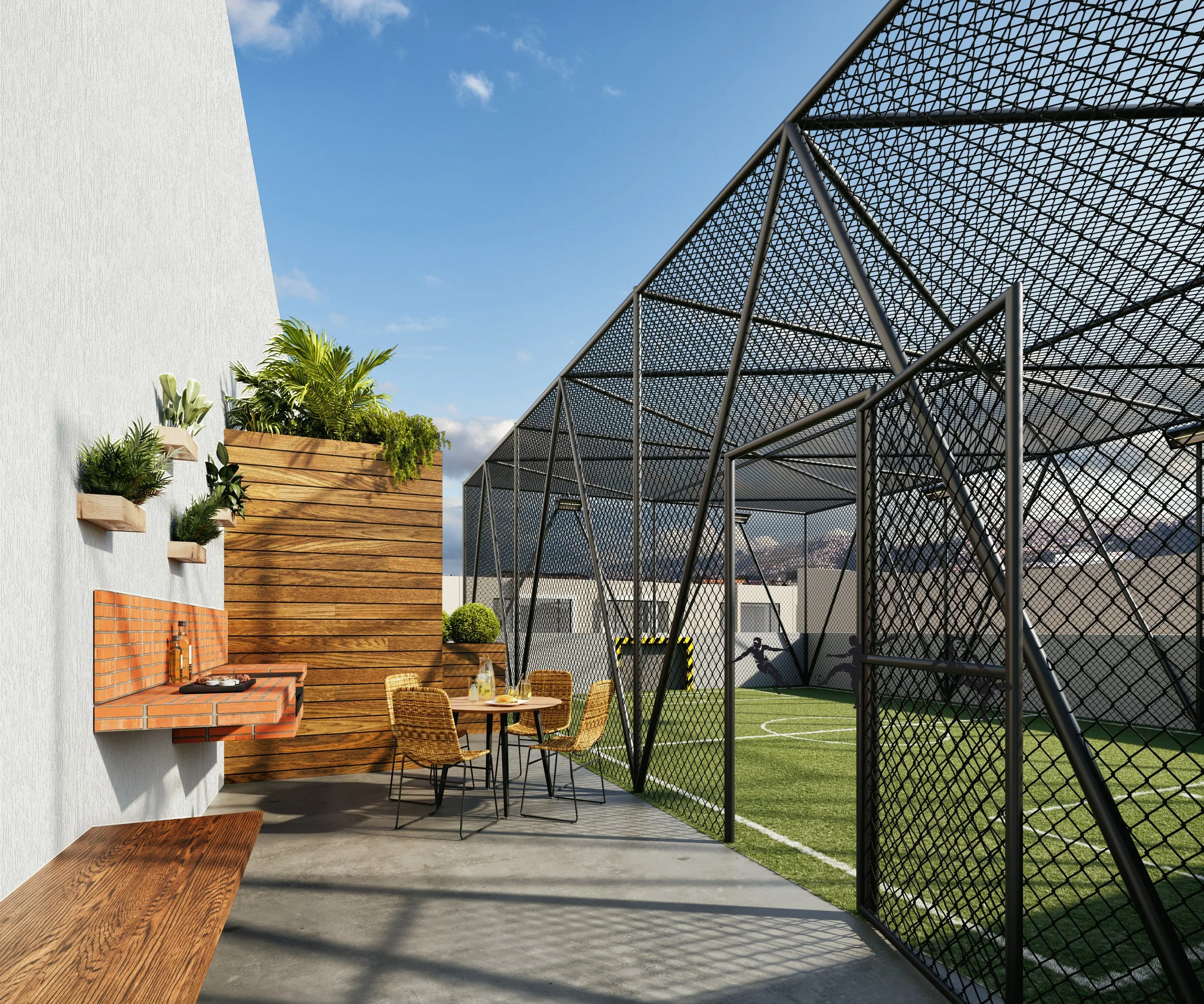 Área de terraza con mesa y sillas de mimbre, paredes decoradas con plantas en macetas de madera, vista a un campo de fútbol en un espacio cerrado con jaula de malla metálica y una pared de madera y pintura blanca.