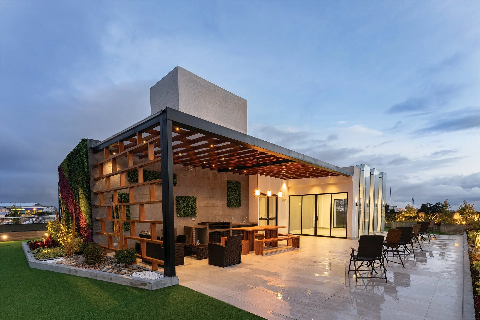 Terraza moderna con mobiliario de jardín, paredes decoradas con plantas y luces de ambiente, en un atardecer lluvioso.