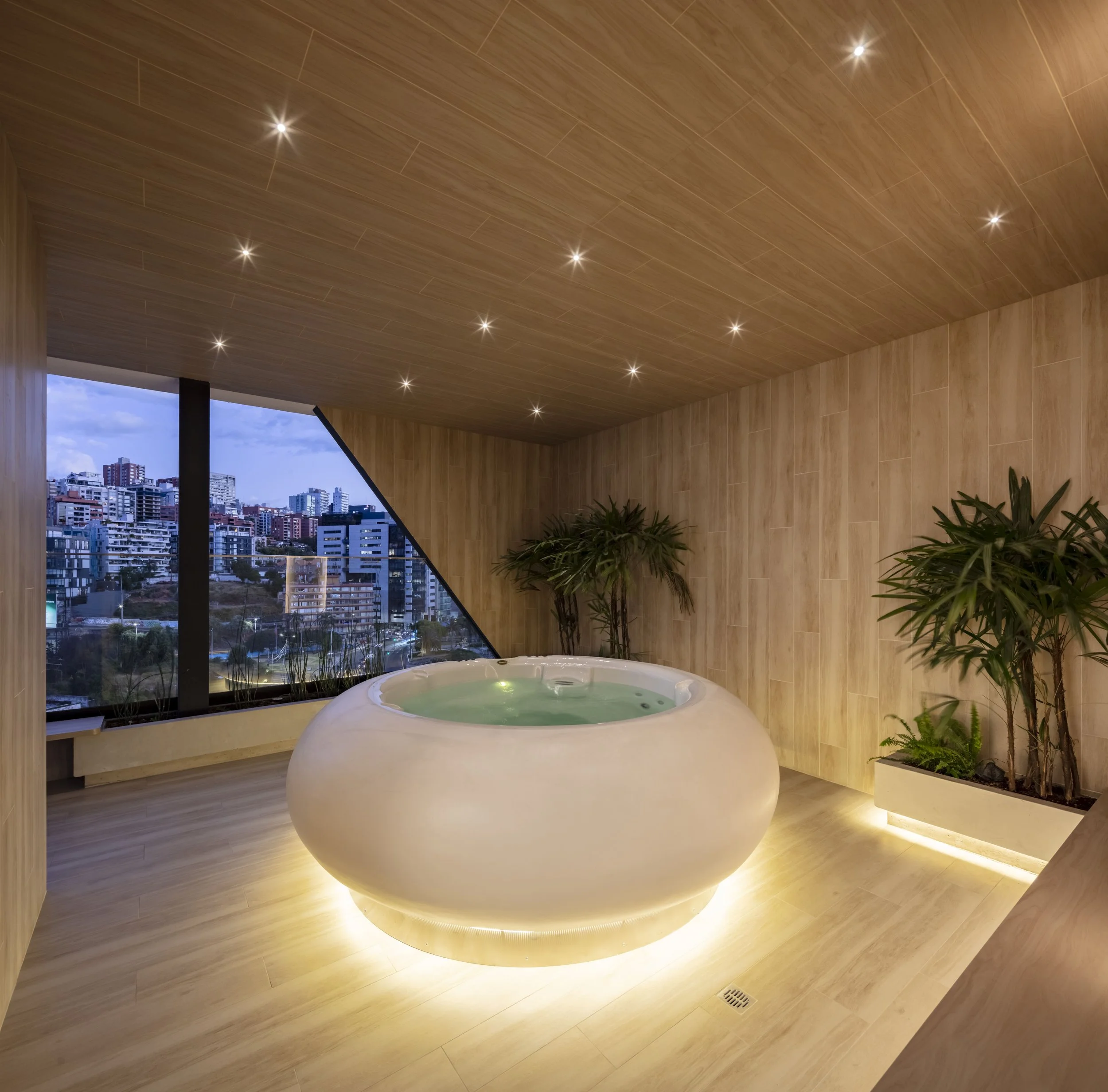 Quito - Ecuador Baño con jacuzzi, paredes y techo de madera, vista a la ciudad a través de una ventana grande.